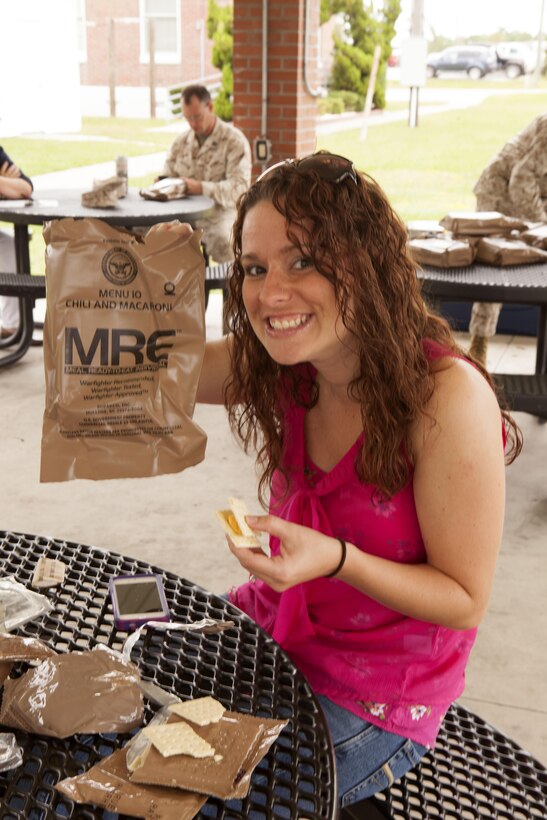 Raven Junge, the spouse of a veteran and Department of Defense employee, shows the Meal Ready to Eat she prepared during Marine Corps Engineer School and the Coast Guard Special Missions Training Center's "In Their Boots Day."