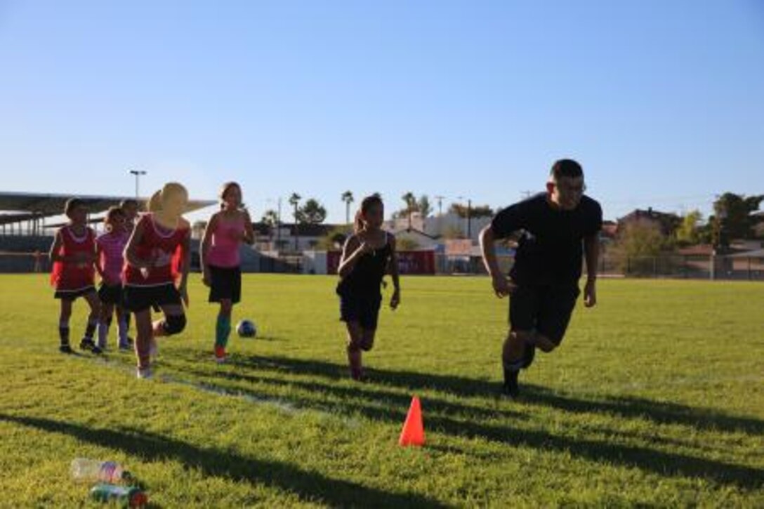 Lance Corporal Brain Ramirez, administrative clerk on Marine Corps Logistics Base Barstow, Calif., and assistant coach for the girls' youth soccer team, "The Galaxy Girls," leads his players in a lap around the practice field, Sept. 23.


