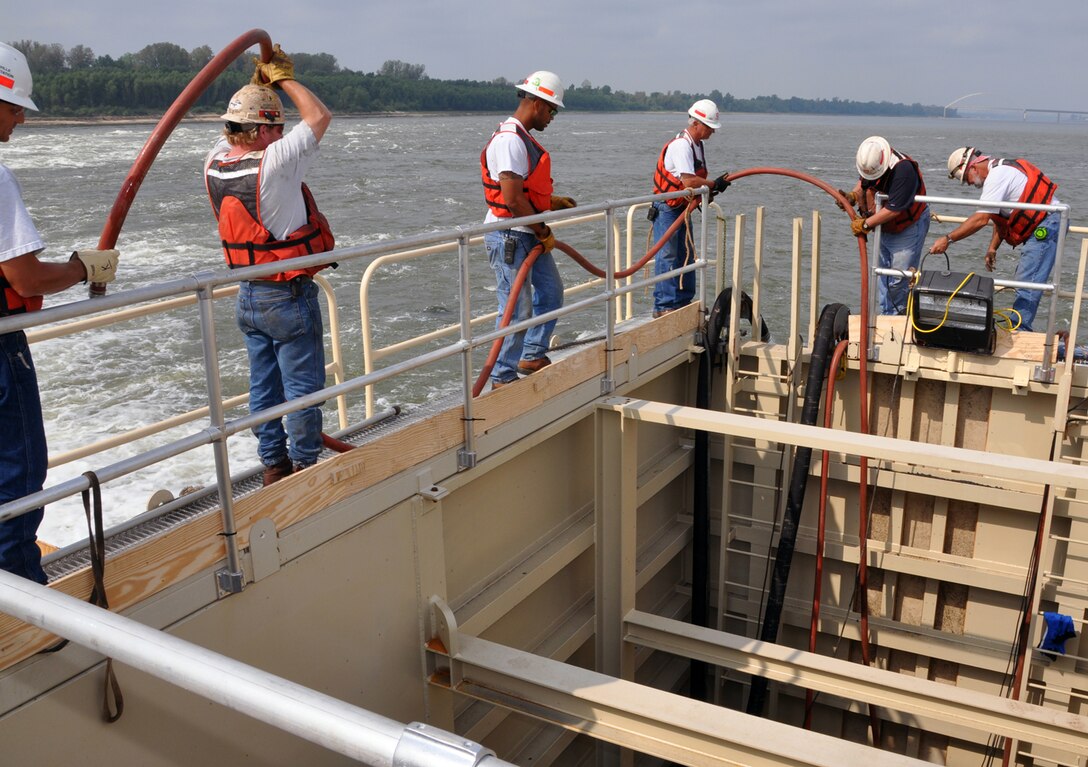 Members of the Louisville repair station hold onto a drainage hose being attached to a pump that will remove water from the new dewatering box set up to repair dam wickets at Locks and Dam 52 on the lower Ohio River Sept. 18.

