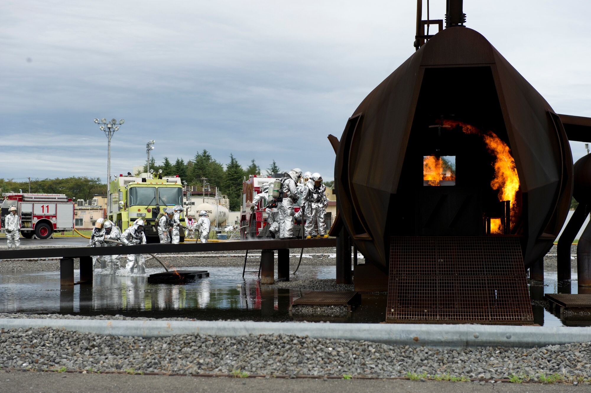 374th Airlift Wing leadership and Firefighters from the 374th Civil Engineer Squadron extinguish a fire on a simulated aircraft, Sept. 26, 2013, during a live-fire training at Yokota Air Base, Japan. The firefighters participate in this type of training to keep their skills sharp and always stay ready for fire emergencies. (U.S. Air Force photo/ Staff Sgt. Stacy Moless/released)