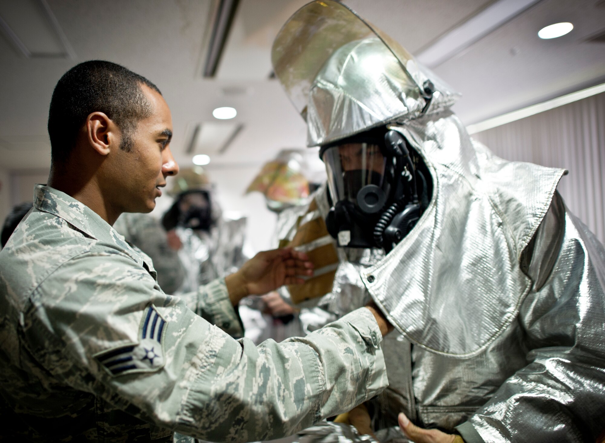 Senior Airman Kiel Carrington, 374th Civil Engenerring Squadron, assists Chief Master Sgt. Manuel Roblesreynoso, 374th Airlift Wing command chief, in donning his bunker gear Sept. 26, 2013 at Yokota Air Base, Japan.  Roblesreynoso is prepairing to partcipate in line-fire training with the Yokota fire fighters. Bunker gear is worn by firefighters to protect them from the scorching temperatures of a fire. (U.S. Air Force photo by Staff Sgt Stacy Moless/released)