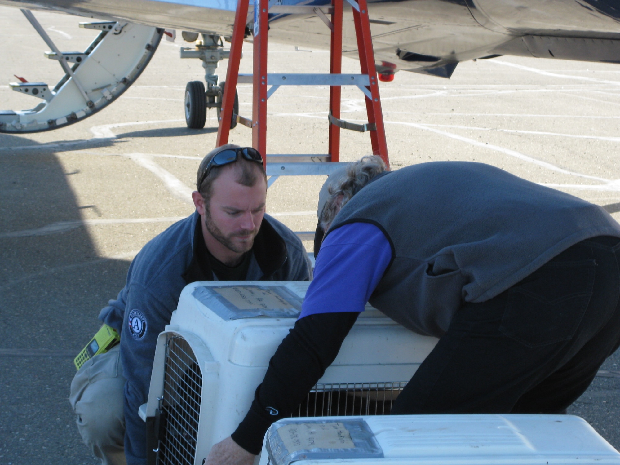 GALENA, Alaska – From left, FEMA Corps team leader Andy John and Jon Bushnell offload Tiny and Cruger from the plane’s cargo hold. The dogs had been housed with Second Chance League in Fairbanks as they waited for a return flight home to Galena (U.S. Air Force photo/Bill Hughes)