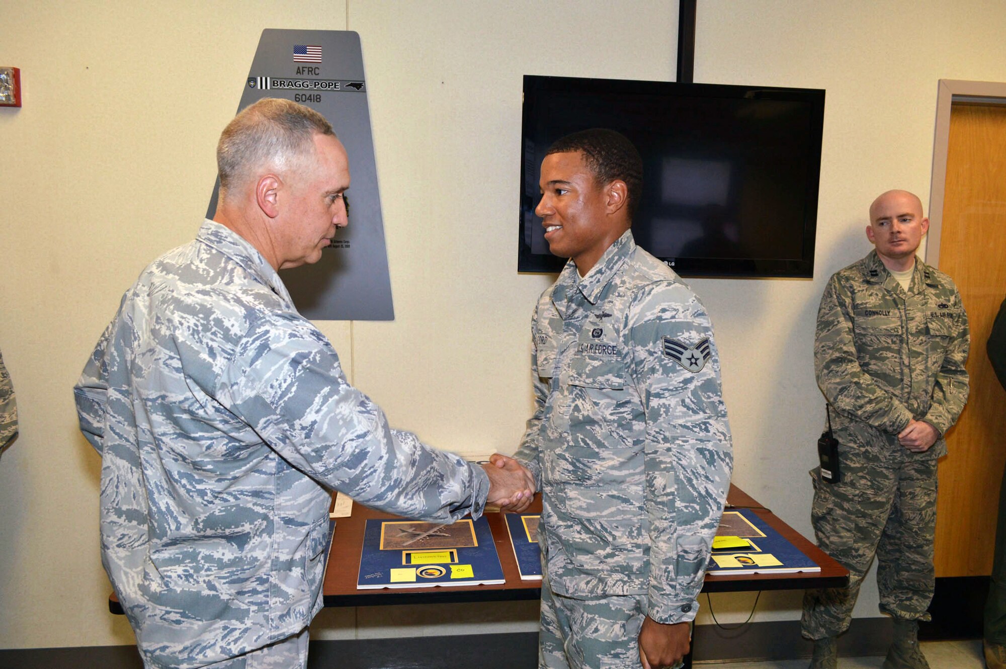 Maj. Gen. Rick Martin, U.S. Air Force Expeditionary Center commander, presents Senior Airman Andrew Ford, 2d Airlift Squadron, with his coin during his tour of 43d Airlift Group units Sep 16.  Airman Ford prepares detailed crew intelligence briefings, including various threat scenarios and reactions, for aircrew members deploying to Southwest Asia.  General Martin visited Pope Army Airfield, N.C. to see first-hand how the 43d Airlift Group Airmen support the Global Response Force mission.  (U.S. Air Force Photo/Marvin Krause)