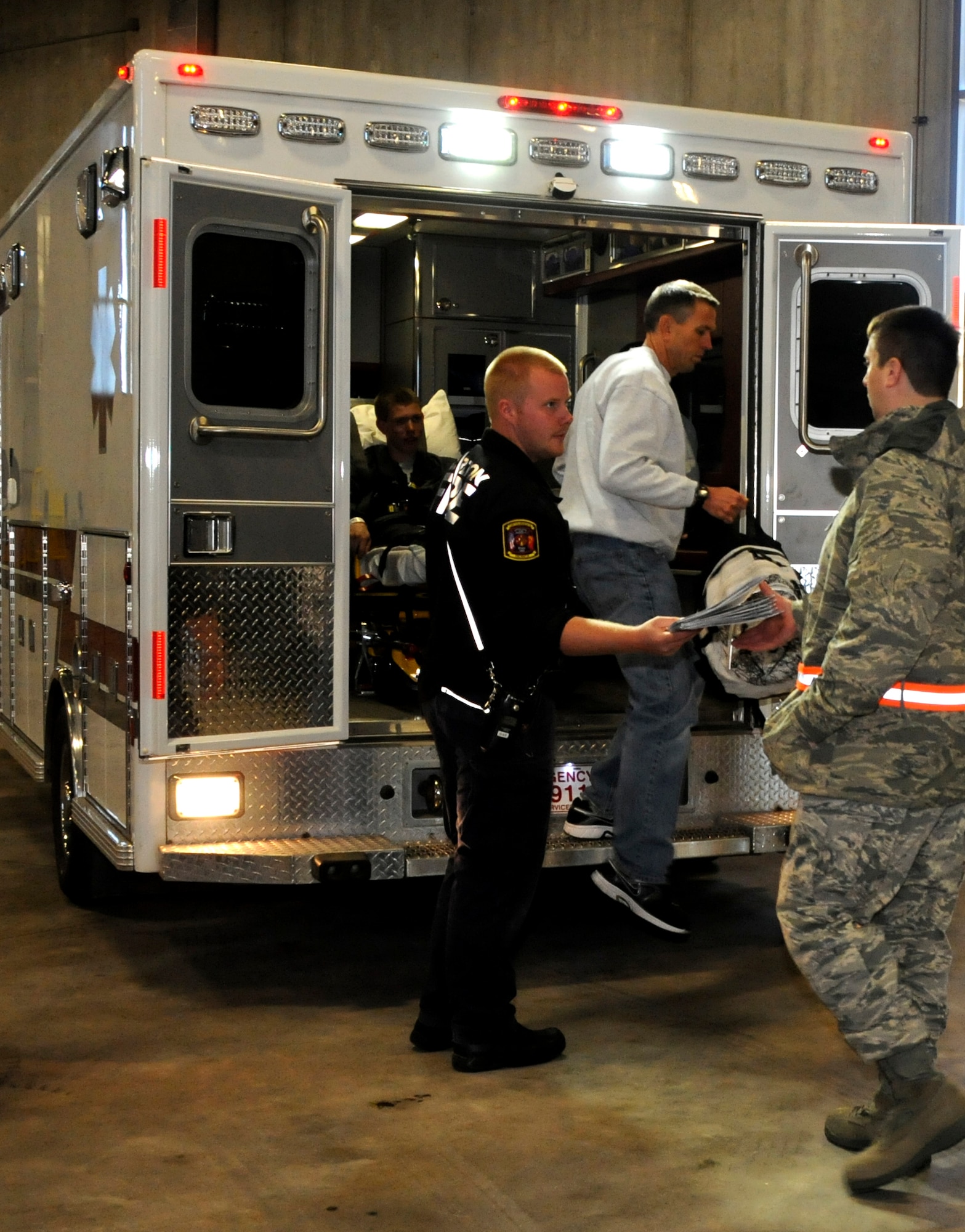 Maj. Michael Cook with the 133rd Airlift Wing and acting Officer in charge of the Enroute Patient Staging System, accepts patient files from the ambulance driver after arriving to the check point.  The exercise simulated a terrorist incident in Duluth that resulted in civilian evacuations to the Twin Cities and Camp Ripley. The training partnered with 14 civilian agencies and utilized many of the 133AW capabilities to help both Airmen and civilians react better when facing disasters. (U.S. Air National Guard photo by Senior Airman Kari Giles.)