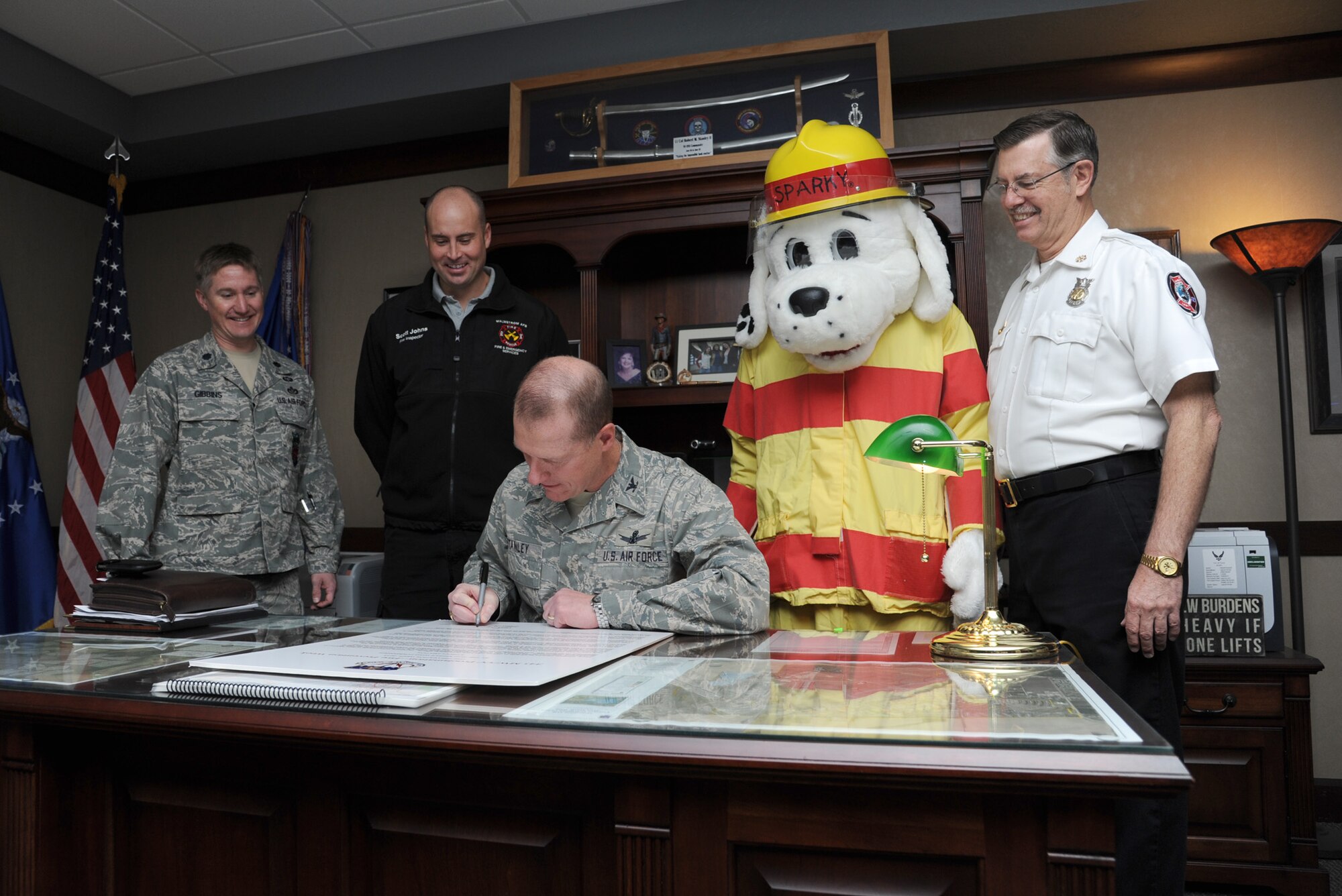 Col. Robert Stanley, 341st Missile Wing commander, signs the 2013 Fire Prevention Week Proclamation. (From left) Lt. Col Walter Gibbins, 341st Civil Engineer Squadron commander; Michael Johns, 341st CES fire inspector; Sparky the Fire Dog; and Daniel Dodson, 341st CES deputy fire chief, look on. Fire Prevention Week starts Oct. 6 and runs through Oct. 12 and will include a children’s fire truck ride, fire safety education briefings and displays, a fire truck parade and the third annual Fire Muster competition. (U.S. Air Force photo/Senior Airman Katrina Heikkinen)