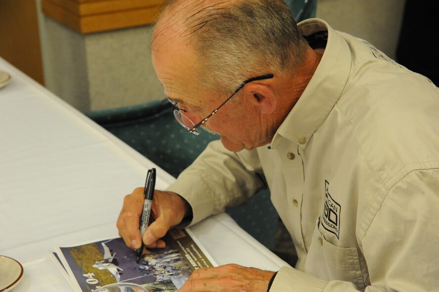 Maj. Gen. (ret.)  Edward Mechenbier, Air Force fighter pilot and Vietnam War prisoner of war, autographs American300 flyers for Airmen after visiting with them at the Elkhorn Dining Facility on Sept 20. Mechenbier was repatriated after being captured. (U.S. Air Force photo/Airman 1st Class Collin Schmidt)  