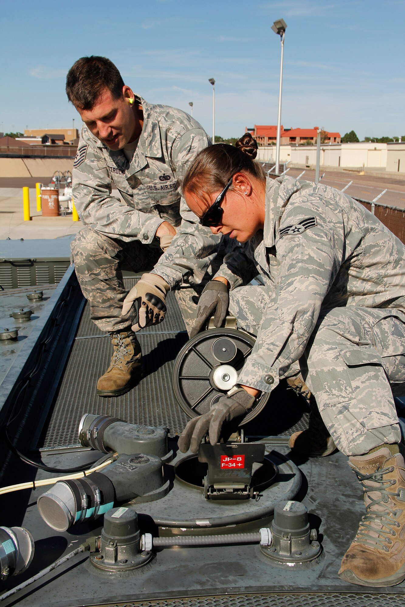 Tech. Sgt. Wade Wittrock, 302nd Logistics Readiness Squadron noncommissioned officer of fuel operations, watches Senior Airman Nicole Lira, 302nd LRS, fuels accountant, verify the fuel quantity is correct through the manhole on top of the R-11 fuel truck.  (U.S. Air Force photo/Staff Sgt. Nathan Federico)