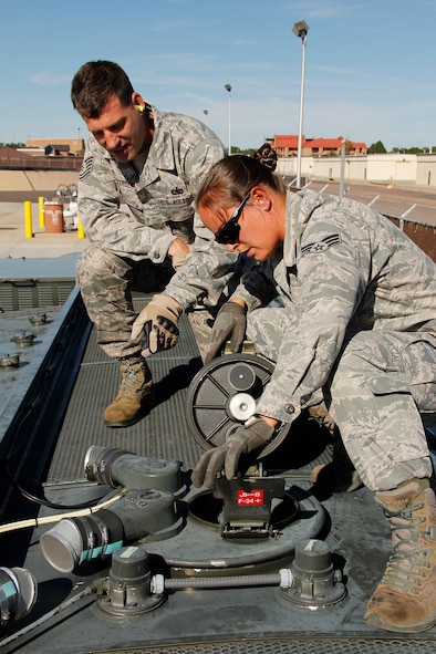 Tech. Sgt. Wade Wittrock, 302nd Logistics Readiness Squadron noncommissioned officer of fuel operations, watches Senior Airman Nicole Lira, 302nd LRS, fuels accountant, verify the fuel quantity is correct through the manhole on top of the R-11 fuel truck.  (U.S. Air Force photo/Staff Sgt. Nathan Federico)