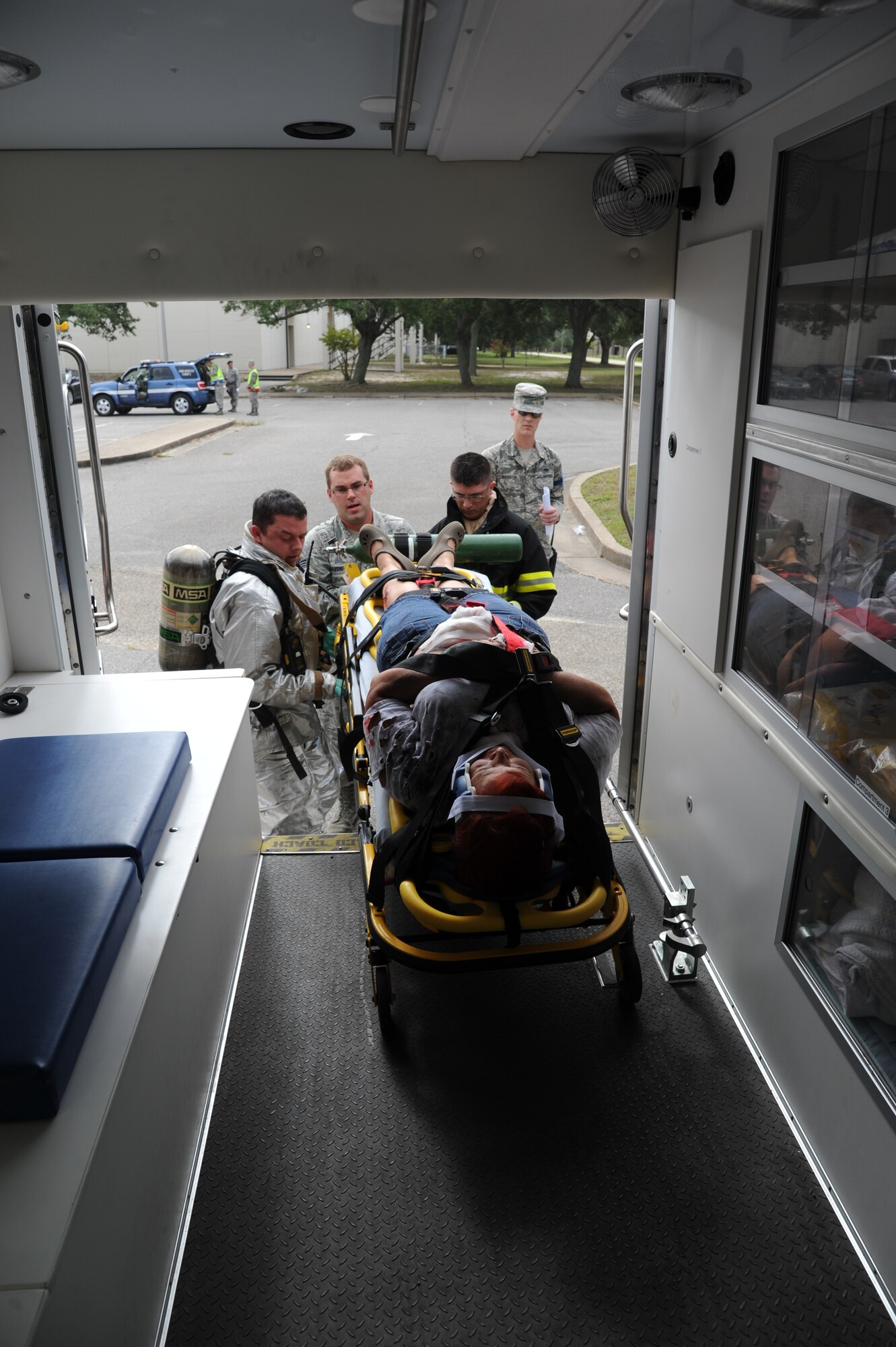 Tech Sgt. Kyle Pourciau, Keesler Fire Department; Senior Airman Andy Davenport, 81st Medical Operations Squadron, and Airman 1st Class Aric Schneeberger, Keesler Fire Department, load Dawn Hitchings, 81st Medical Group, into the back of an ambulance to be transported to the Keesler Medical Center during a structure fire exercise Sept. 25, 2013, Keesler Air Force Base, Miss. The scenario consisted of a simulated explosion in a boiler room causing a fire to spread rapidly throughout the building trapping and injuring five role players.  (U.S. Air Force photo by Kemberly Groue)