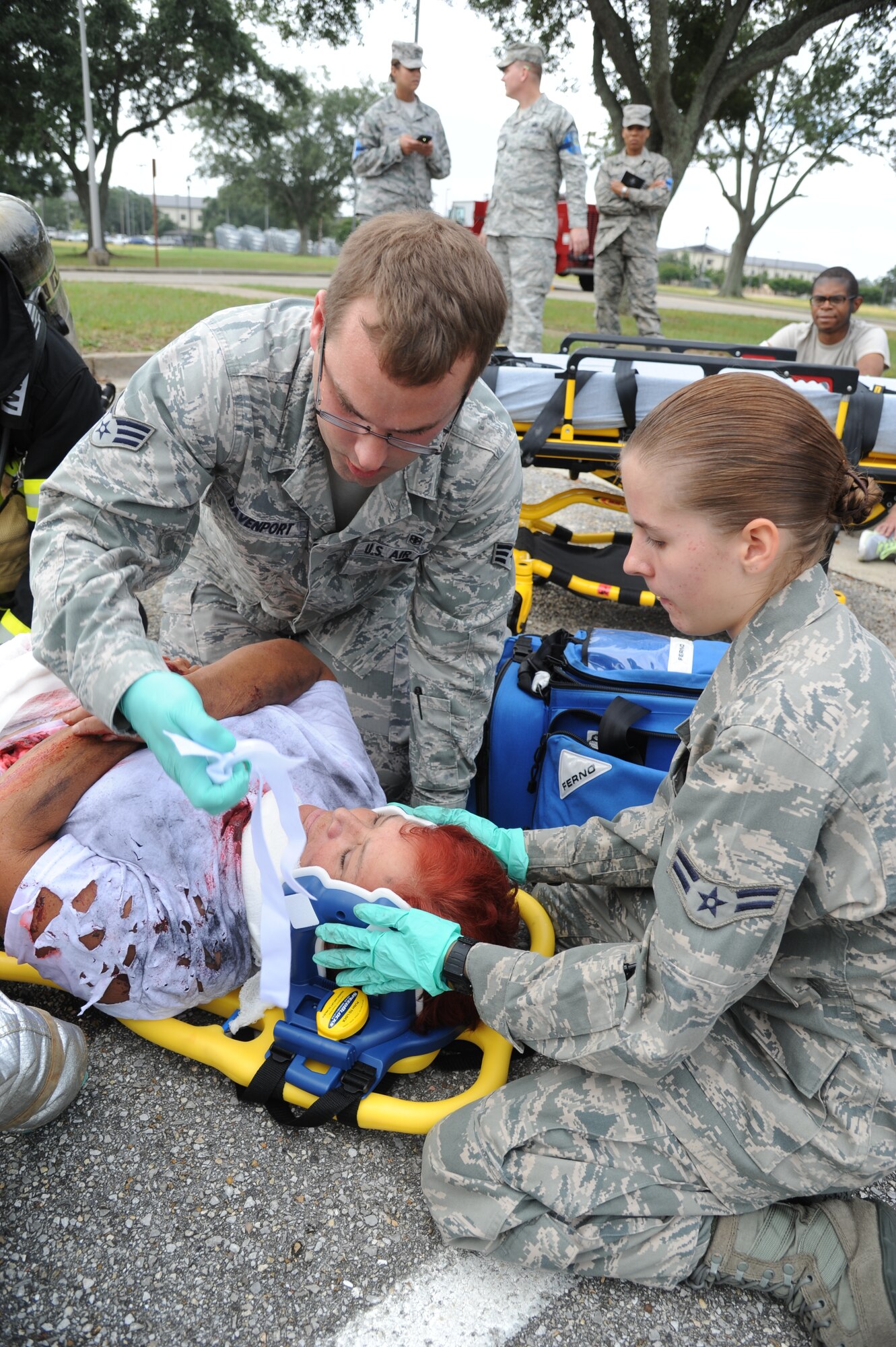 Senior Airman Andy Davenport, 81st Medical Operations Squadron, and Airman 1st Class Brittni Jones, 81st Medical Support Squadron, secure the neck of Dawn Hitchings, 81st Medical Group, to be transported to the Keesler Medical Center during a structure fire exercise Sept. 25, 2013, Keesler Air Force Base, Miss.  The scenario consisted of a simulated explosion in a boiler room causing a fire to spread rapidly throughout the building trapping and injuring five role players.  (U.S. Air Force photo by Kemberly Groue)