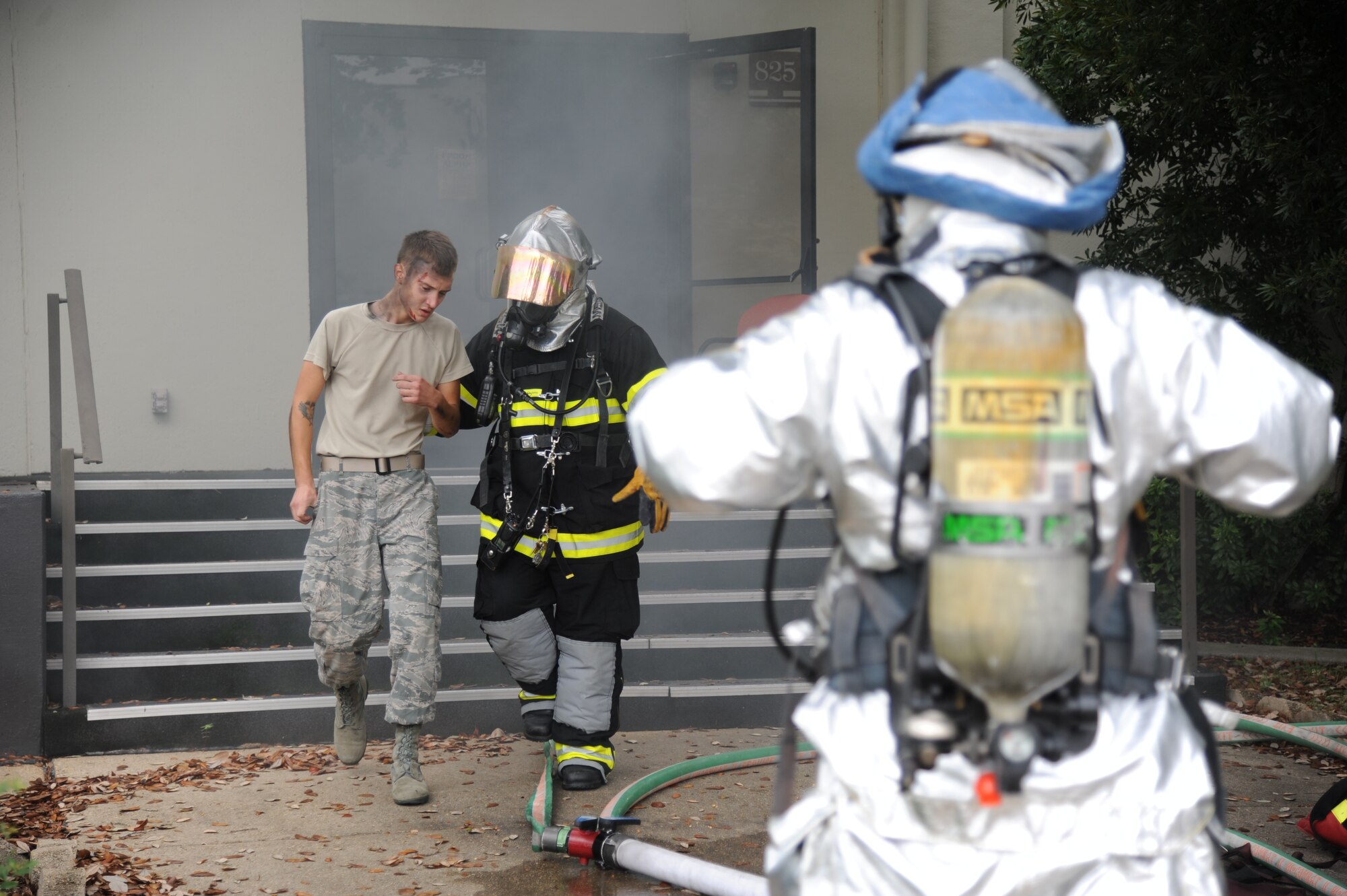 Airman 1st Class Austen Koczent, 81st Medical Operations Squadron, is escorted out of a building by John McIntyre, Keesler Fire Department, to receive medical attention in the triage area during a structure fire exercise Sept. 25, 2013, Keesler Air Force Base, Miss. The scenario consisted of a simulated explosion in a boiler room causing a fire to spread rapidly throughout the building trapping and injuring five role players.  (U.S. Air Force photo by Kemberly Groue)