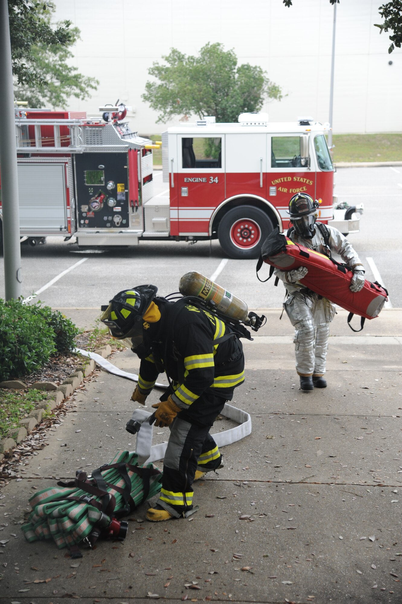 John McIntyre and Christopher Oliver, Keesler Fire Department, stage attack hoses prior to entering a building during a structure fire exercise Sept. 25, 2013, at Keesler Air Force Base, Miss. The scenario consisted of a simulated explosion in a boiler room causing a fire to spread rapidly throughout the building trapping and injuring five role players.  (U.S. Air Force photo by Kemberly Groue)