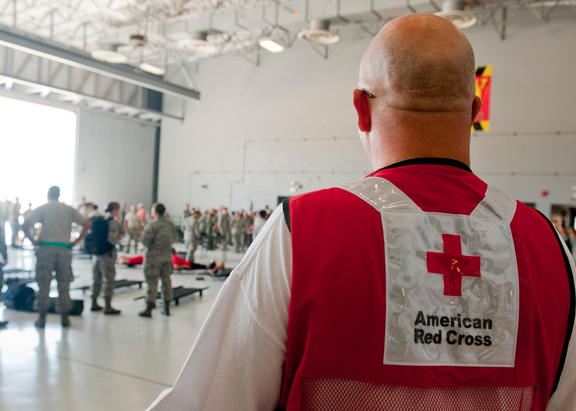 A volunteer from the American Red Cross watches Sept. 20, 2013, as Airmen participating in the Federal Coordination Center Exercise prepare to receive simulated patients at the medical staging point at Nellis Air Force Base, Nev. Members of the Red Cross supported the Southern Nevada exercise by handing out water and lunch to participants. (U.S. Air Force photo by Staff Sgt. Michael Charles)