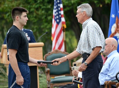 A U.S. Air Force service member delivers the Prisoner of War/Missing in Action baton to James M. Lindsey the brother of Col. Marvin N. Lindsey who has been MIA since 1965, September 20 at Joint Base San Antonio-Lackland. The Airman run a 24 hr. relay race which culminates in a baton handoff to awaiting families members of past and present POW/MIA's. (U.S. Air Force photo by Benjamin Faske/released)