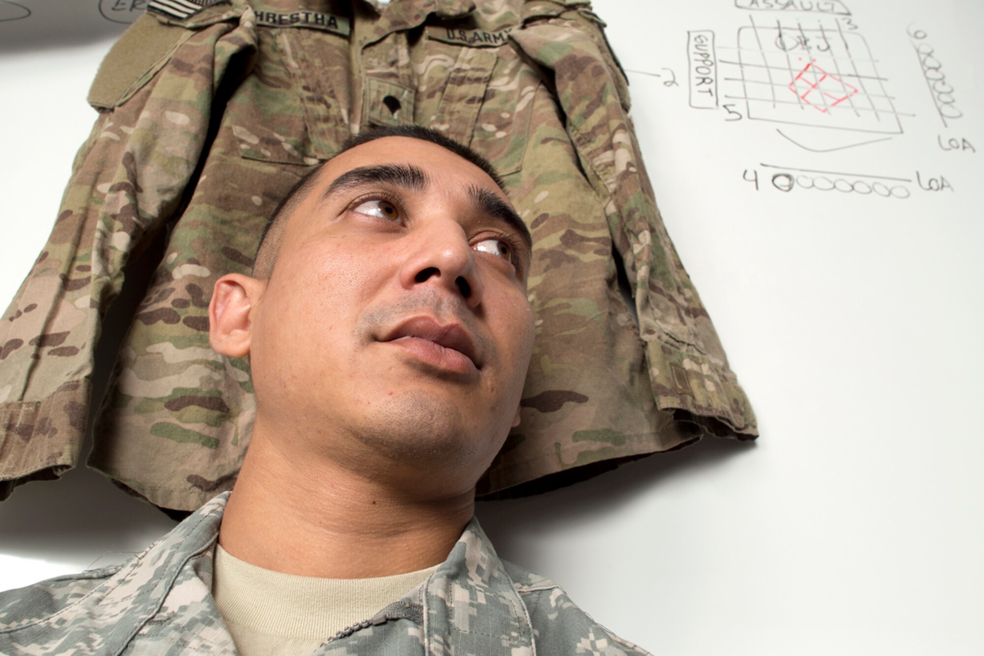 Spc. Bijesh Shrestha, an Army ROTC cadet at the University of Alaska Anchorage and native of Malangawa, Nepal, wears his cadet uniform and is framed by the uniform he wore during an Afghanistan deployment with JBER's 425th Brigade Special Troops Battalion. Shrestha is enrolled in the Green to Gold Active Duty Option Program and expects to commission in May 2015. (U.S. Air Force photo/David Bedard)
