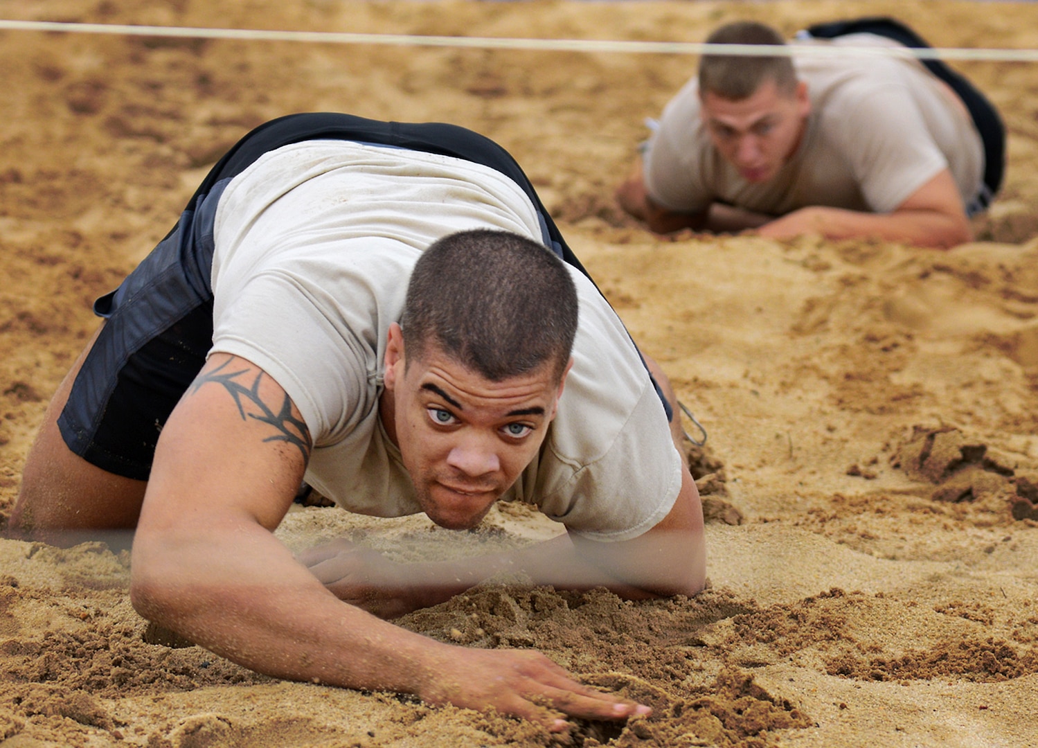 Members of team Wu-Tang, low crawl through the sand pit during the field exercises portion of the  Community Quest race September 18, at Joint Base San Antonio-Lackland. (U.S. Air Force photo by Benjamin Faske/released)