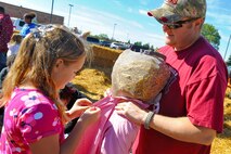 Tech. Sgt. Jeff Morris, 5th Contracting Squadron noncommissioned officer in charge of Construction Flight, helps his daughter Hannah put together a scarecrow during the 15th Annual Fall Festival held at the Exchange parking lot, Sept. 21. Hosted by the 741st Missile Squadron Gravel Hauler’s Association, the event is put together in part as a fundraiser, as well as a way to bring Airmen and their families together in a day of family activities. (U.S. Air Force photo/Senior Airman Jose L. Hernandez)