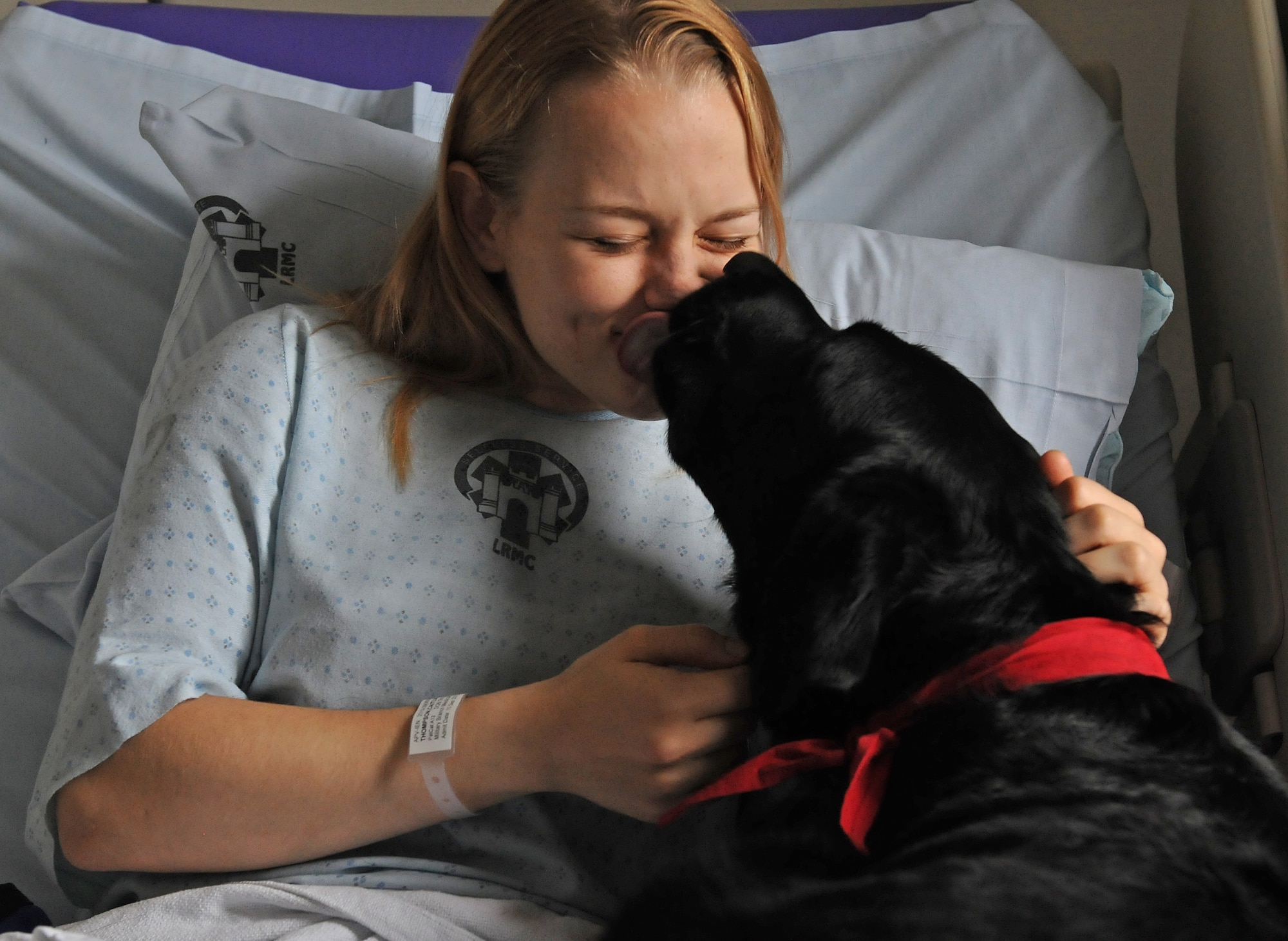 Cpl. Caitlin Thompson, a reservist with the 450th Military Police Squadron, receiving treatment for injuries sustained while deployed to Kuwait, spends time with Tank, a 2-year-old black Labrador retriever, during a Pets and Warriors visit, Sept. 18, 2013, Landstuhl Regional Medical Center. The PAW program allows volunteers and their pets to visit wounded warriors and other patients in the hospital to boost their morale. (U.S. Air Force photo/Airman 1st Class Holly Mansfield)