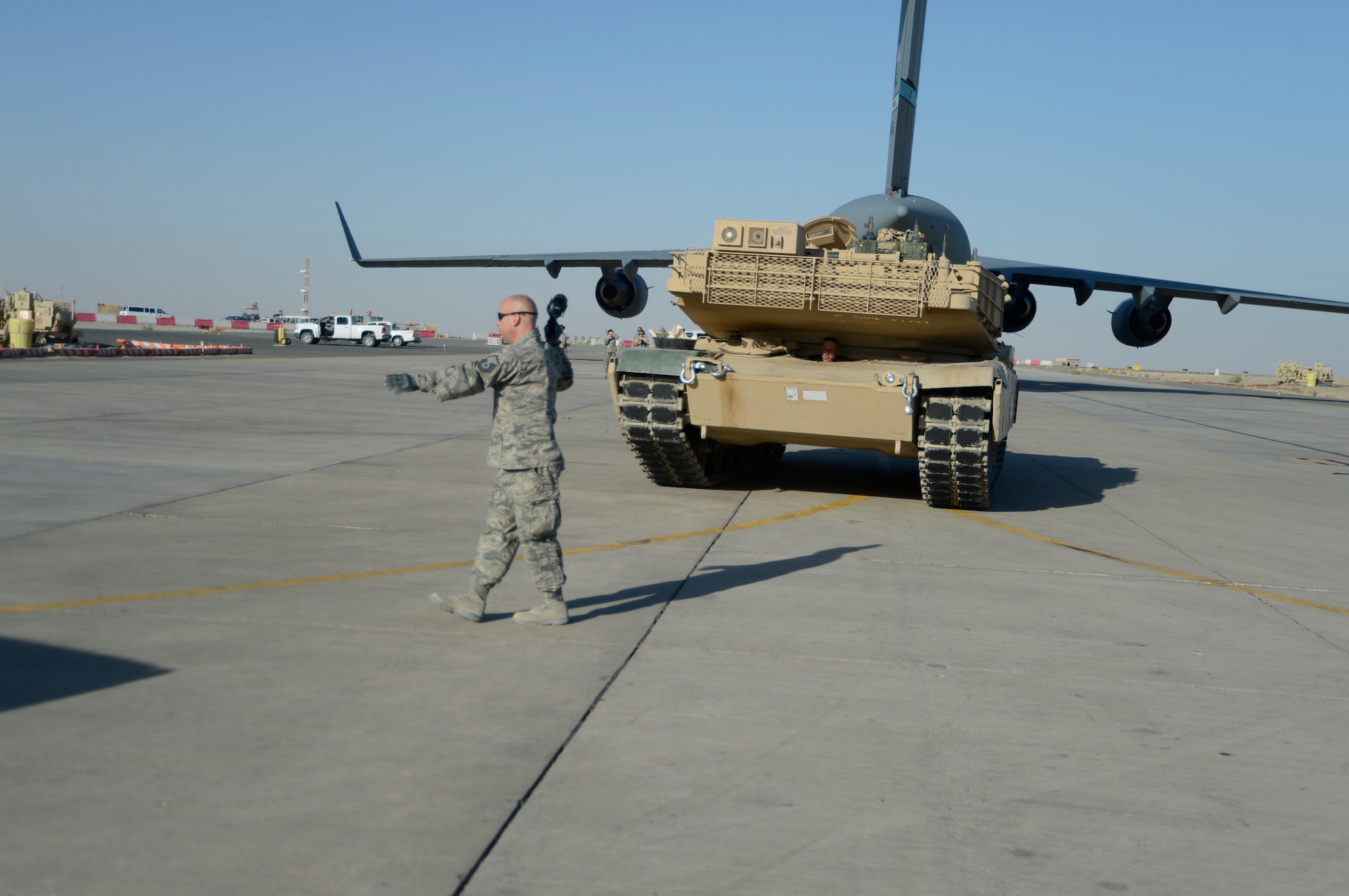Master Sgt. Bradley Hayes, 386th Expeditionary Logistics Readiness Squadron ramp operations noncommissioned officer in charge, directs an M-1 tank following its offload at an undisclosed location in Southwest Asia, Sept. 26, 2013.  Ramp personnel at the 386th Air Expeditionary Wing on average handle more than 3,000 tons of cargo each month.  (U.S. Air Force photo by Master Sgt. Chris Campbell)