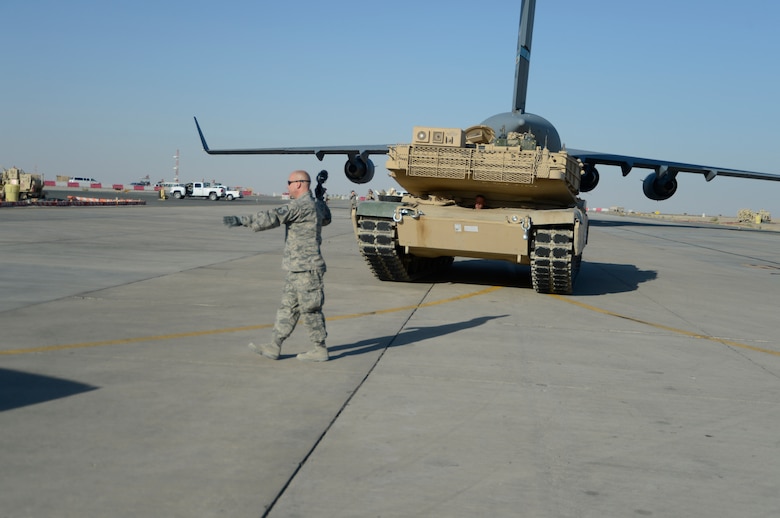 Master Sgt. Bradley Hayes, 386th Expeditionary Logistics Readiness Squadron ramp operations noncommissioned officer in charge, directs an M-1 tank following its offload at an undisclosed location in Southwest Asia, Sept. 26, 2013.  Ramp personnel at the 386th Air Expeditionary Wing on average handle more than 3,000 tons of cargo each month.  (U.S. Air Force photo by Master Sgt. Chris Campbell)
