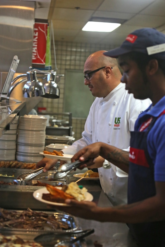 Rahm Fama, guest chef and host of the Food Network show, "Meat and Potatoes," serves up an array of meat and starch dishes at the 14 Area mess hall aboard Camp Pendleton, Calif., Sept. 25, 2013. Fama taught the food service specialists ways to enhance their culinary skills and provided them with a view on the food industry from a civilian perspective. 