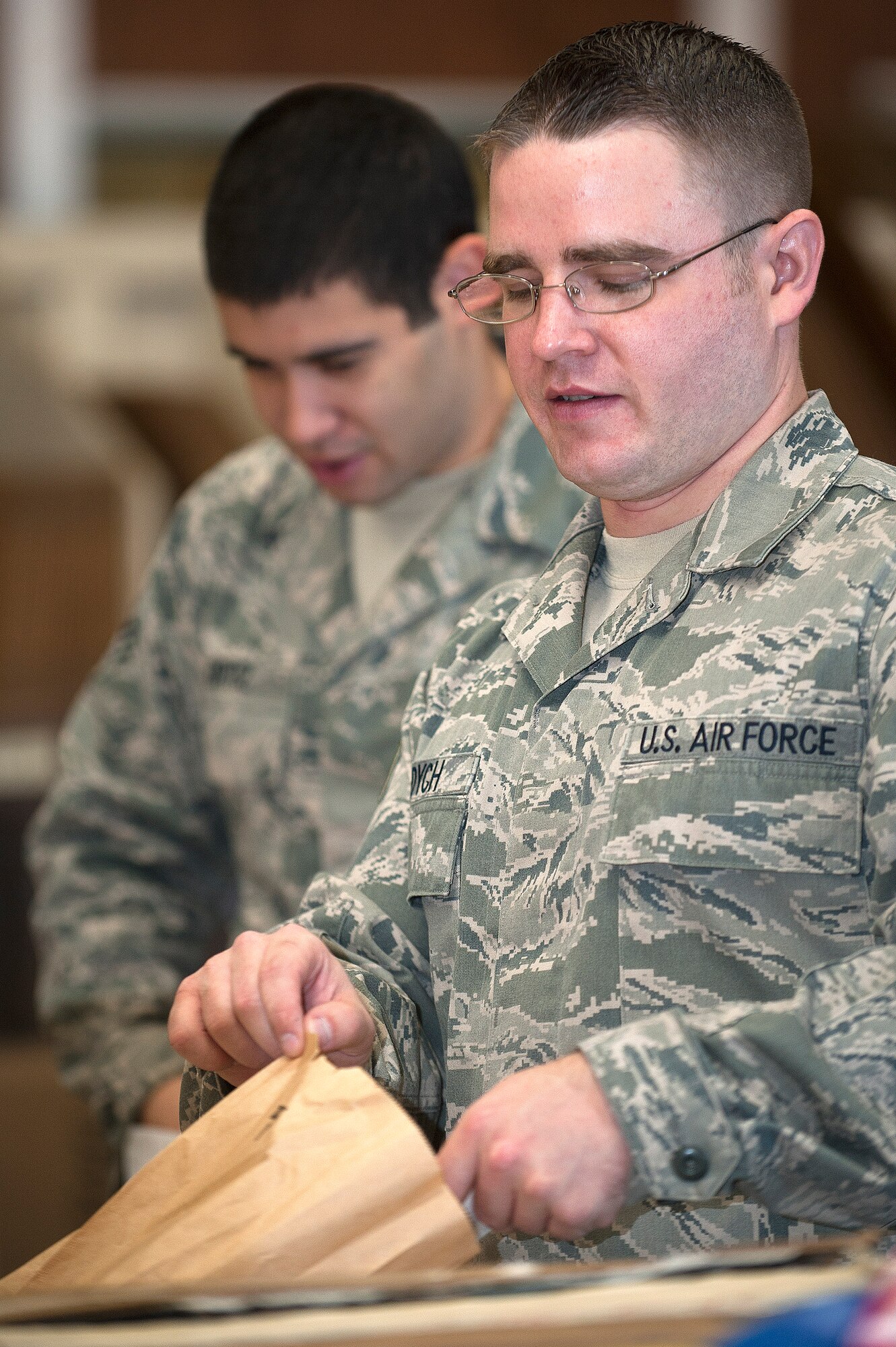 Senior Airman Joseph Tadych (foreground) and Senior Airman Donovan Ortiz (background), 99th Logistics Readiness Squadron outbound cargo traffic management journeymen, prepare packages for movement at LRS Sept. 27, 2013, at Nellis Air Force Base, Nev. Tadych and Ortiz also identify whether to move cargo through DHL Worldwide Network, Federal Express, or United Parcel Service to ensure the best method of transportation is used. (U.S. Air Force photo by Staff Sgt. Christopher Hubenthal)