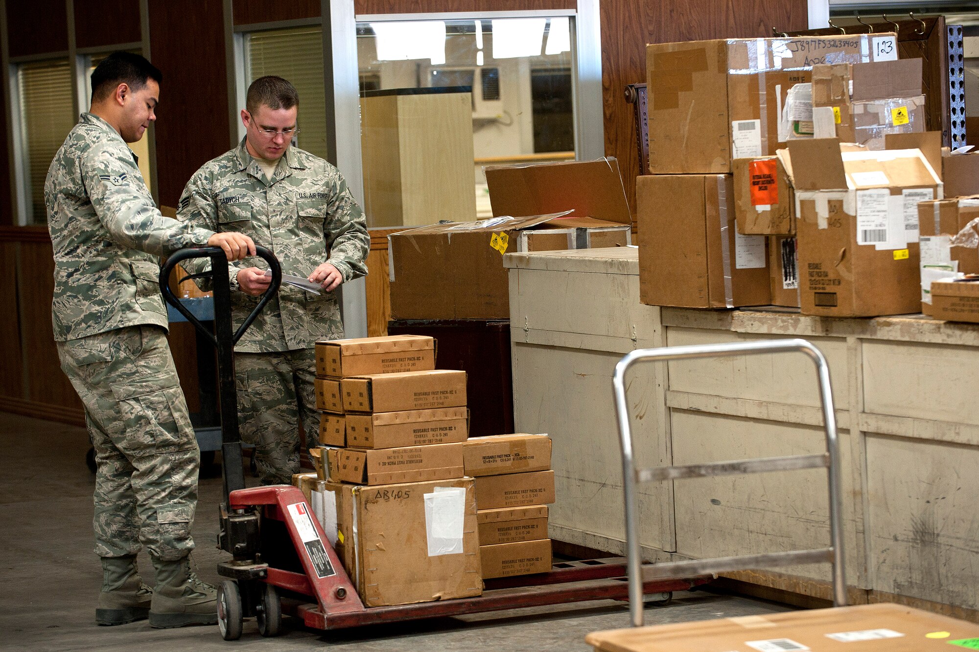 Airman 1st Class Kevin Illastron (left), 99th Logistics Readiness Squadron flight service center supply management apprentice, and Senior Airman Joseph Tadych (right), 99th LRS outbound cargo traffic management journeyman, prepare cargo for movement at LRS Sept. 27, 2013, at Nellis Air Force Base, Nev. Airmen of the 99th LRS who work with cargo at Nellis AFB can prepare items for movement as small as an O-Ring to as large as an aircraft engine. (U.S. Air Force photo by Staff Sgt. Christopher Hubenthal)