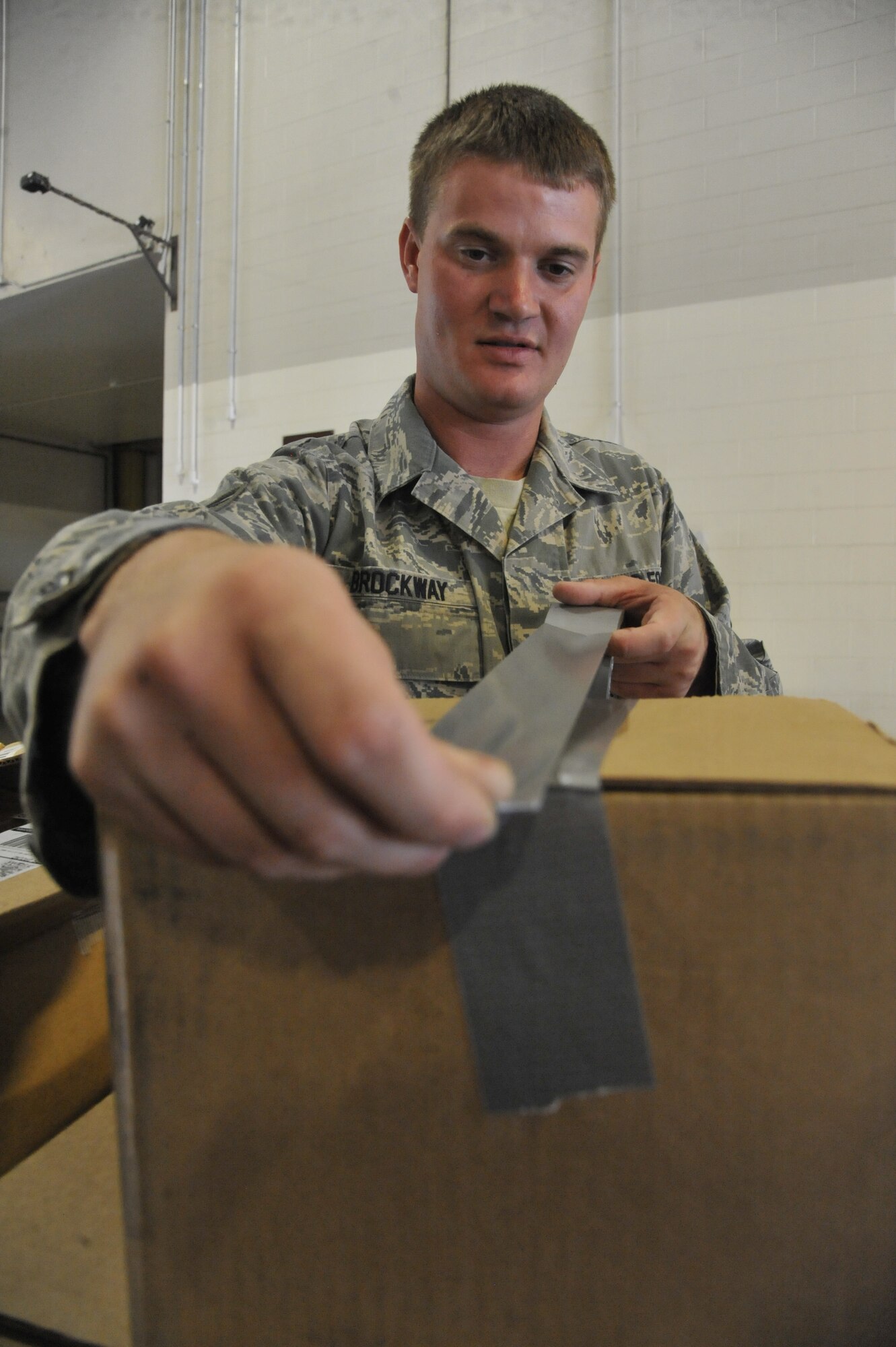 U.S. Air Force Staff Sgt. Chris Brockway, 442nd Logistics Readiness Squadron traffic management apprentice, tapes a package at Whiteman Air Force Base, Mo., Sept. 23, 2013. All packages must be secured and delivered to the customer in a timely manner. (U.S. Air Force photo by Airman 1st Class Keenan Berry/Released)