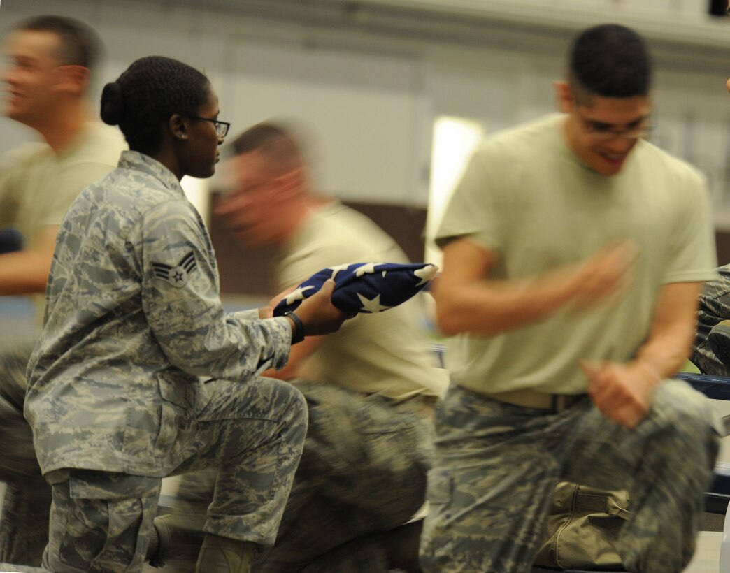 Senior Airman Erika Williams, 28th Logistics Readiness Squadron deployment and training technician, practices handing off the U.S. flag during an honor guard training course in the Pride Hangar at Ellsworth Air Force Base, S.D. Sept. 19, 2013. During the course, Williams and other trainees faced a series of challenges, such as several people moving around them at one time, designed to hone their ability to maintain their military bearing. (U.S. Air Force photo by Airman 1st Class Rebecca Imwalle/Released)