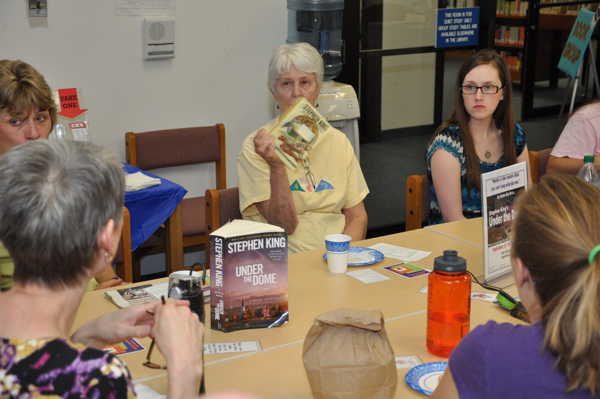 Carol Cop, former Luke library technician, holds up her copy of a Stephen King novel during the book club for adults discussion at the library Sept. 12. The group selected this month to read any novel written by author Stephen King. (U.S. Air Force photo/Staff Sgt. Luther Mitchell)