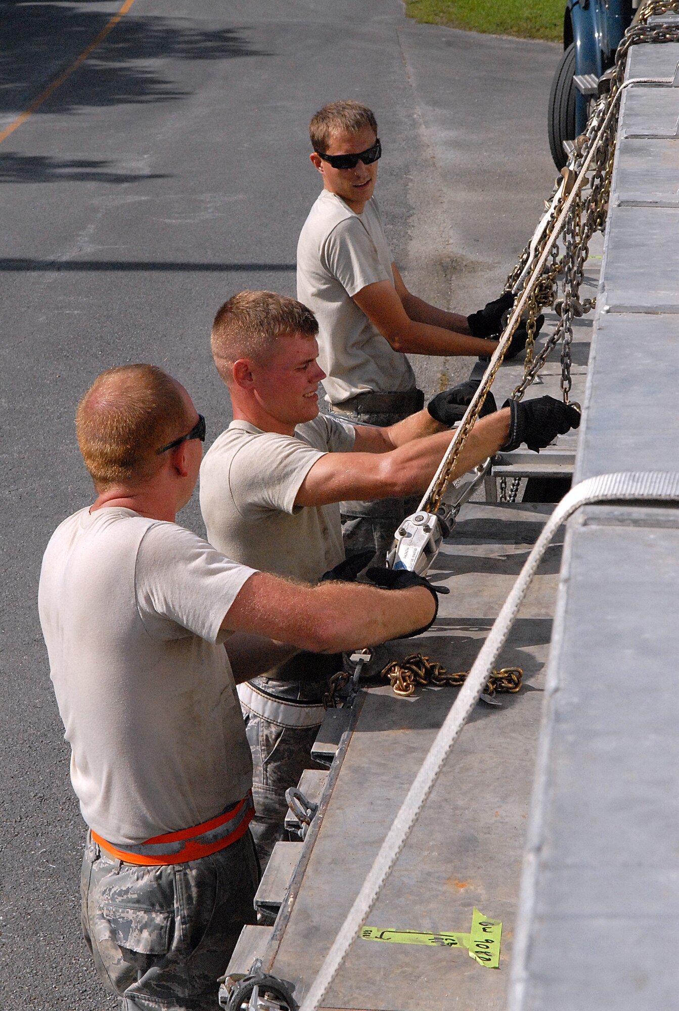 U.S. Air Force Staff Sgt. David Meadows, and Airmen 1st Class Devin Lagarce and Chad Lambeth, 18th Munitions Squadron Tactical Ammunition Rapid Response Package crew members, tighten chains and straps to secure munitions during a local exercise on Kadena Air Base, Japan, Sept. 24, 2013. The TARRP exercise tests the squadron to prove they are ready to supply missiles for transport. (U.S. Air Force photo by Staff Sgt. Lauren Snyder)