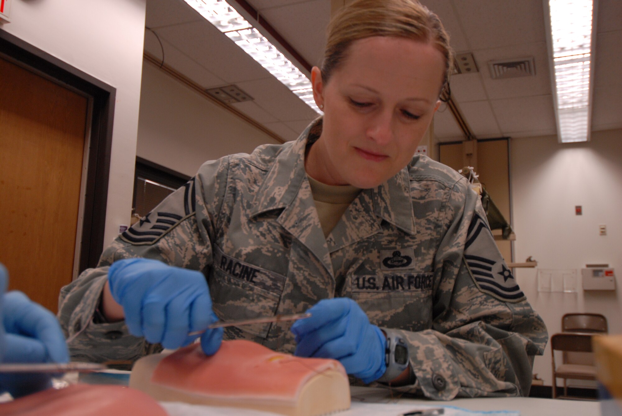 Senior Master Sgt. Kathlina Racine, 303rd Intelligence Squadron superintendent, learns how to apply stitches to a wound while visiting the 51st Medical Group during a Mustang Immersion tour at Osan Air Base, Republic of Korea, Sept. 26, 2013. The Mustang Immersion tour aimed to promote cohesion among members of Team Osan. (U.S. Air Force photo/1st Lt. Kay M. Nissen)