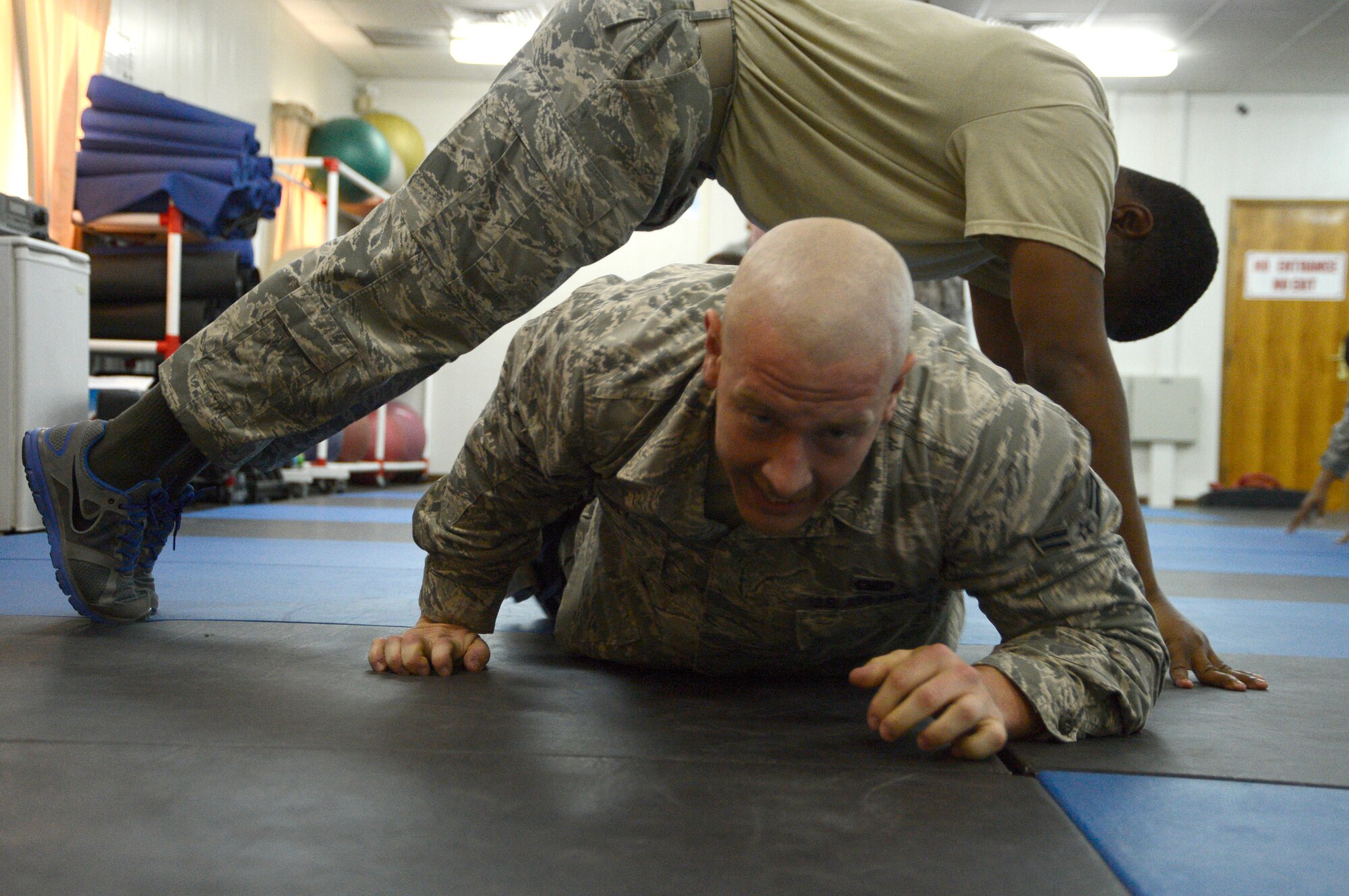 Tech. Sgt. Antroine Lovett, 386th Air Expeditionary Wing, check six facilitator, provides a bridge for Airman 1st Class Matthew Sebey, 387th Expeditionary Security Forces Squadron, to crawl under as part of a combatives class here, Sept. 19, 2013.  The exercise is called the egg jump and crawl. One partner takes an egg shape on the floor, the other person jumps over him/her. The person on the ground then makes a bridge shape and their partner crawls underneath.  Lovett is deployed out of the 802nd Security Forces Squadron, Lackland Air Force Base, San Antonio, Texas, and is a native of Monroe, La. Sebey is deployed out of the 2nd Security Forces Squadron, Battle Creek, Mich., and is a native of Stanton, Ky. (U.S. Air Force photo by Master Sgt. Christopher A. Campbell)