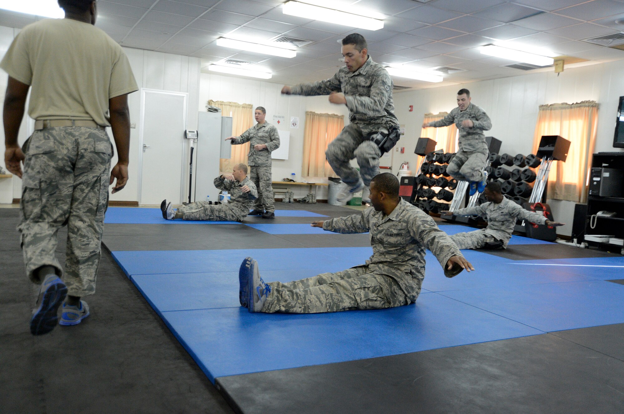 Members of the 386th Air Expeditionary Wing combatives class execute the t-jump exercise here, Sept. 19, 2013. The t-jump consists of one partner sitting on the ground with their arms raised. The other partner jumps over one arm, their partner’s legs and finally the other arm in succession to complete one repetition.  The class was required to finish 15 repetitions of this exercise before moving to the next stage. (U.S. Air Force photo by Master Sgt. Christopher A. Campbell)