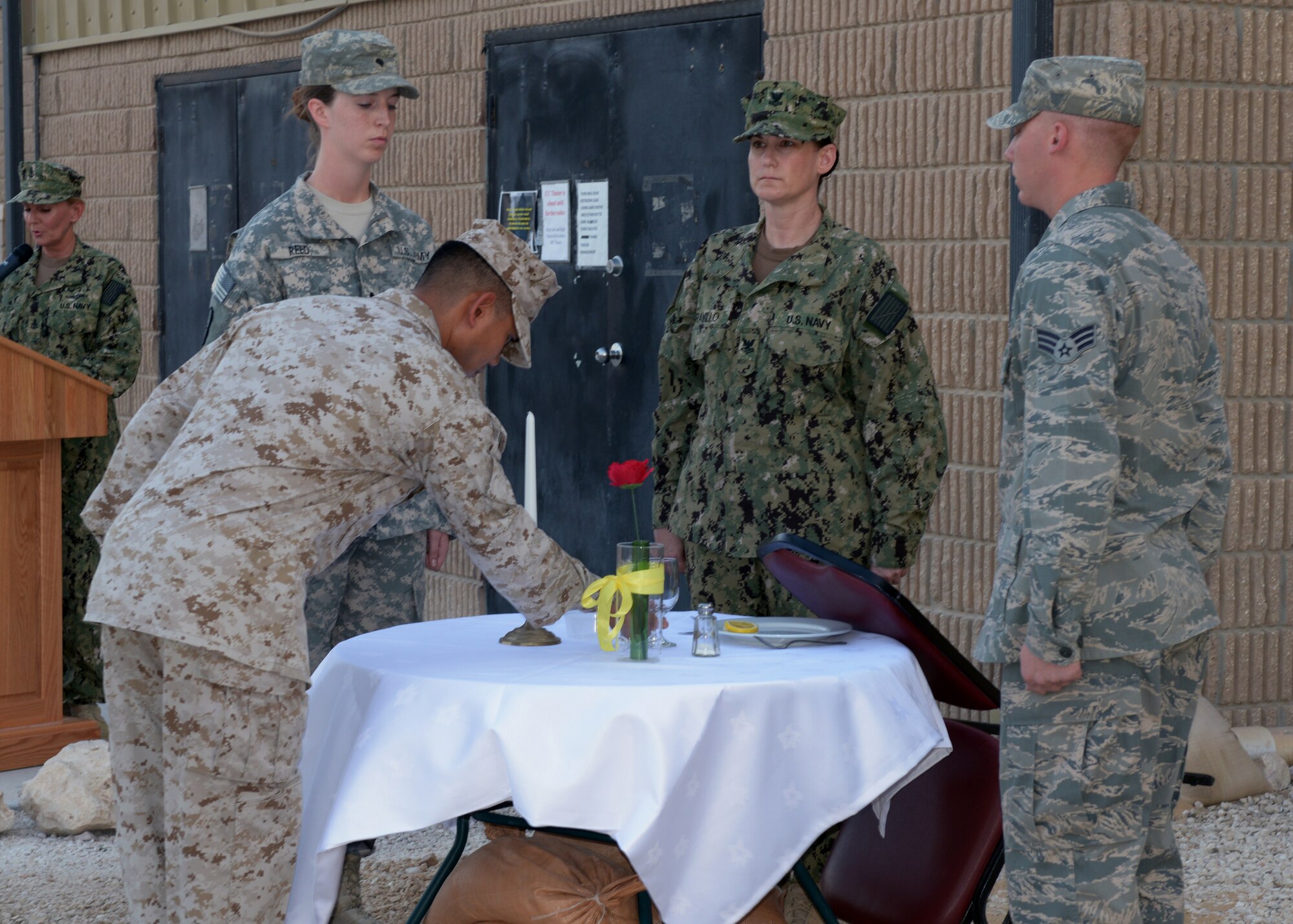 Service members representing the Army, Navy, Marine Corps and Air Force prepare place setting at a table during a prisoner of war and missing in action remembrance ceremony at the 379th Air Expeditionary Wing in Southwest Asia, Sept. 20, 2013. Each part of the place setting (a rose, a pinch of salt, an overturned glass and a slice of lemon) has a special meaning, and the table is reserved to honor missing comrades in arms. (U.S. Air Force photo/Senior Airman Bahja J. Jones) 