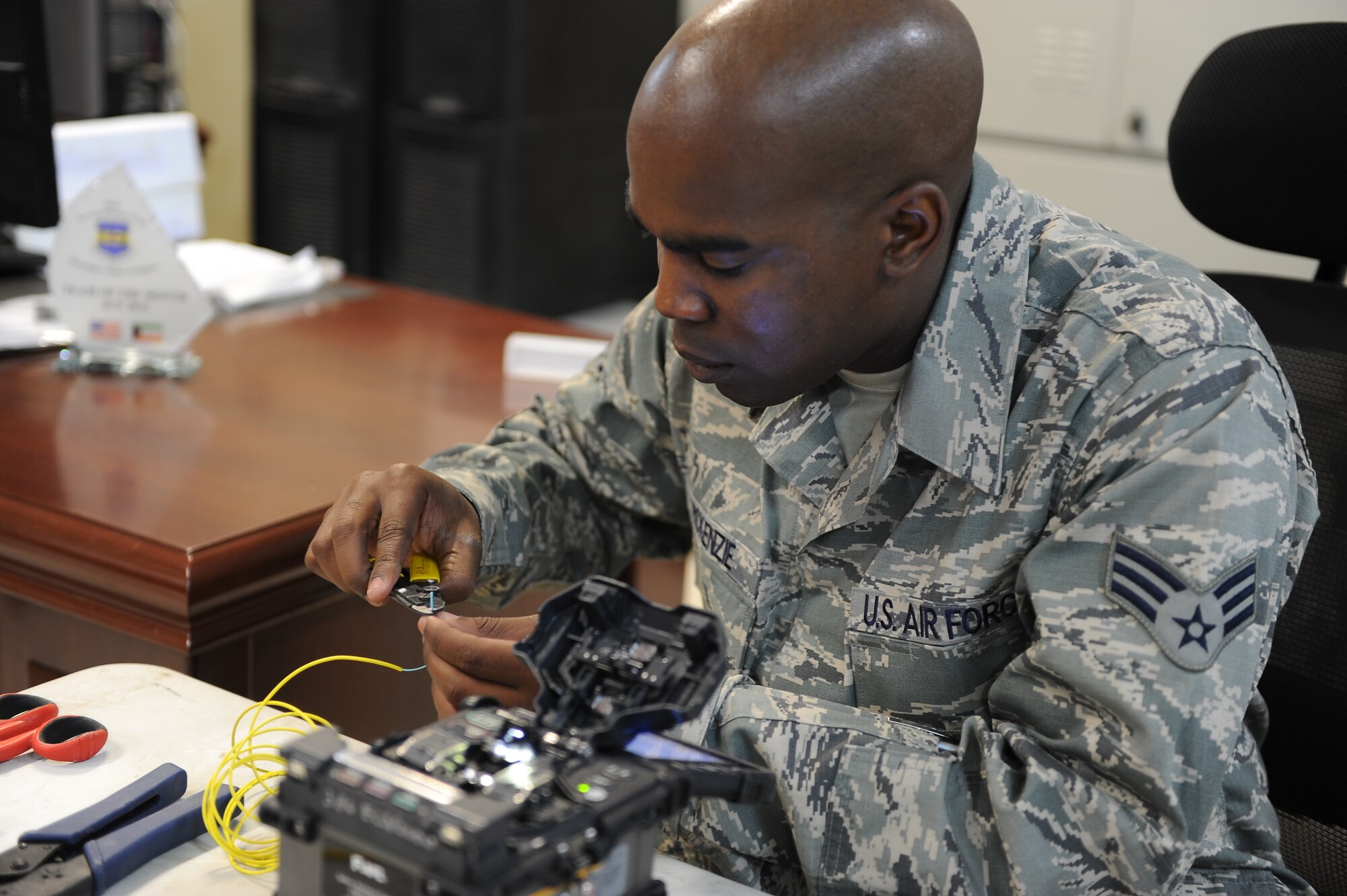 Senior Airman Armand McKenzie, 386th Expeditionary Communications Squadron cable antenna systems technician, splices fiber optic cables here, Sept. 16, 2013.  According to McKenzie, splicing cable requires a great deal of attention to detail in the best of conditions.  However, doing it in the sandy, windy elements at his deployed location in Southwest Asia adds another level of challenge because the smallest piece of dirt can be the difference between a good cable and a bad one.  McKenzie is deployed from Eglin Air Force Base, Fla.  He is a native of Salinas, Calif.  (U.S. Air Force photo by Master Sgt. Marelise Wood) 
