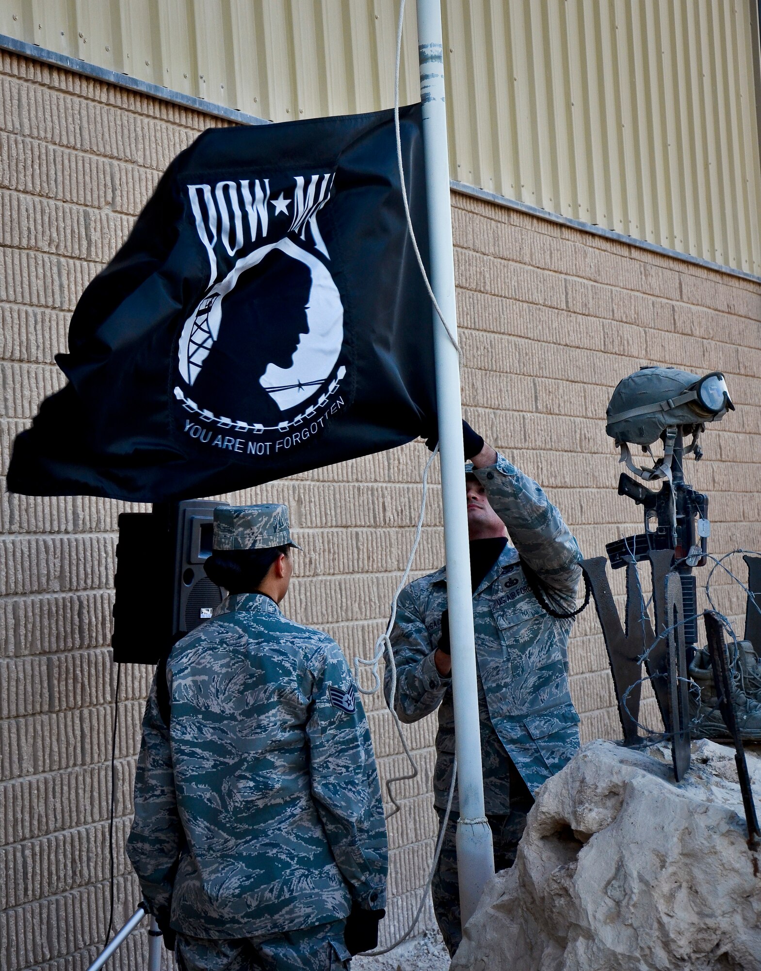 Staff Sgts. Vanessa Dominguez and Ernest McGachey secure the prisoners of war and missing in action flag during a remembrance ceremony at the 379th Air Expeditionary Wing in Southwest Asia, Sept. 21, 2013. In the United States, National POW/MIA Recognition Day is observed on the third Friday in September and honors those who were prisoners of war and those who are still missing in action. Dominguez is assigned to the 379th Expeditionary Force Support Squadron, deployed from March Air Reserve Base, Calif., and hails from El Centro, Calif. McGachey is assigned to the 71st Expeditionary Air Control Squadron and deployed from Spangdahlem Air Base, Germany. (U.S. Air Force photo/Staff Sgt. Benjamin W. Stratton)