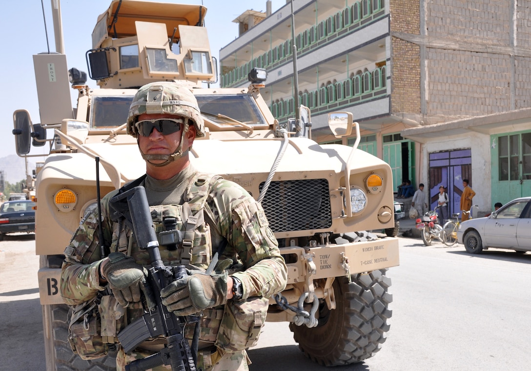 U.S. Army Sgt. 1st Class Edward Ward stands watch near an armored all-terrain vehicle as supplies are unloaded for children at the Farah Orphanage in Farah City, Afghanistan, Sept. 26, 2013.