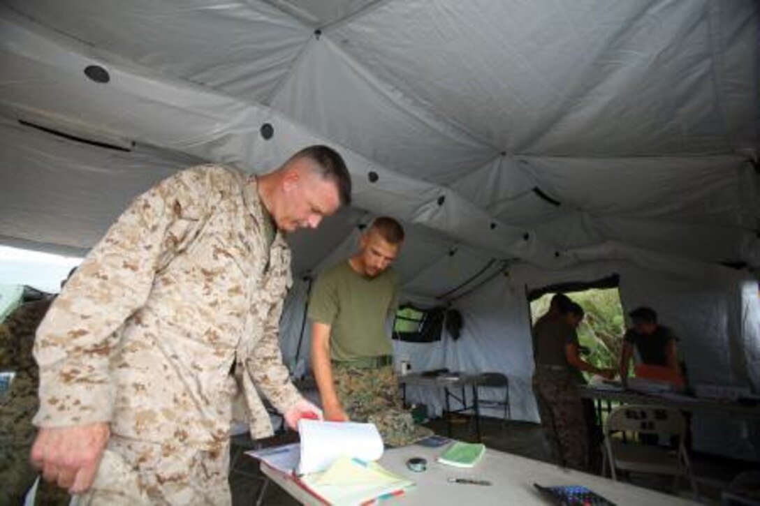 Brig. Gen. Niel E. Nelson, left, reviews operational documents with Sgt. Damon R. Wheeler Sept. 18 at Landing Zone Dodo in the Central Training Area. Nelson is the commanding general of 3rd MLG, and Wheeler is an ammunition technician with Ammunition Co.


