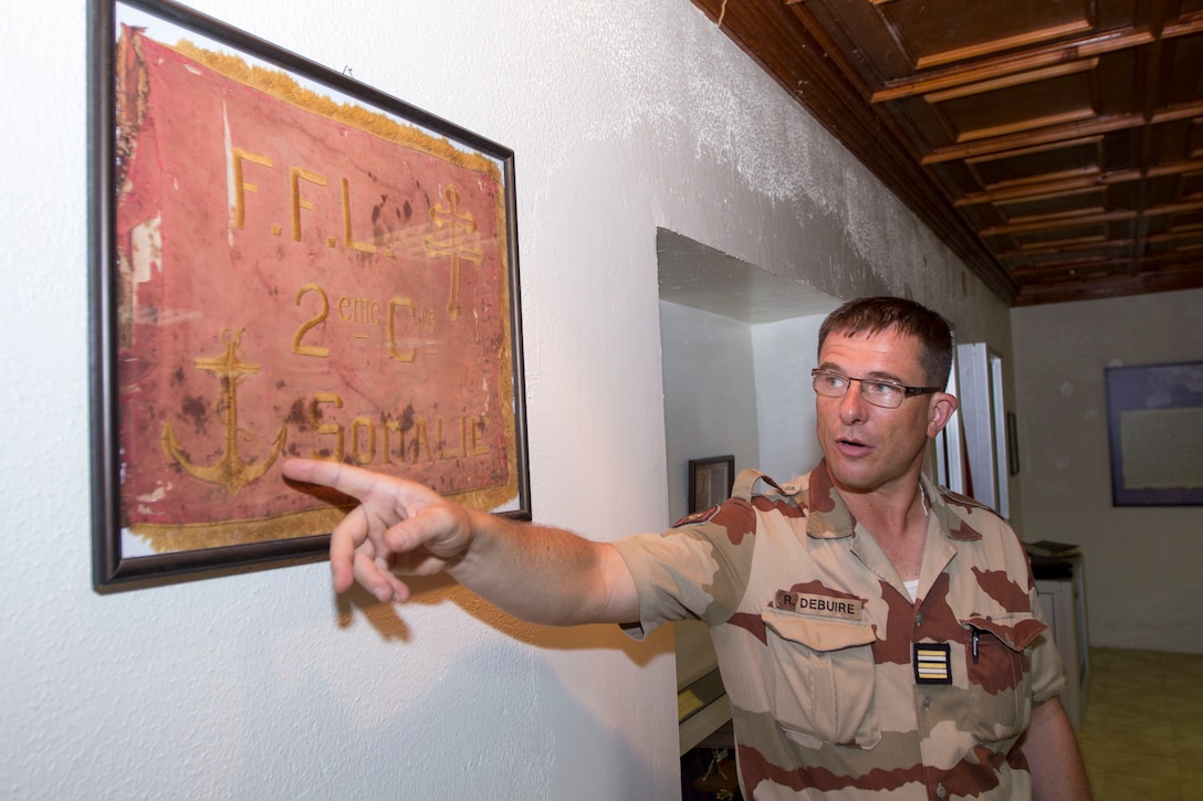 French Lt. Col. Renee Debuire, French exchange officer assigned to the 26th Marine Expeditionary Unit (MEU), explains the history of the French Fifth Marine Regiment aboard Camp Lemonnier, Djibouti, Sept. 27, 2013. The 26th MEU is a Marine Air-Ground Task Force forward-deployed to the U.S. 5th and 6th Fleet areas of responsibility aboard the Kearsarge Amphibious Ready Group serving as a sea-based, expeditionary crisis response force capable of conducting amphibious operations across the full range of military operations. (U.S. Marine Corps photo by Cpl. Kyle N. Runnels/Released)