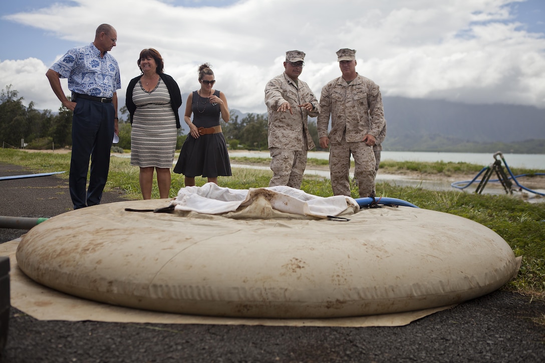 Sgt. Kevin Rodriguez, water chief for Combat Logistics Battalion 3, (second from right), explains part of the process saltwater goes through while in the Tactical Water Purification System during a presentation at Landing Zone Westfield aboard Marine Corps Base Hawaii, Sept. 17, 2013. (From left to right): Mark Dungan, deputy director of the Operations and Training Directorate, Jacqueline Freeland, director, Mission Assurance Force Protection Office, MCB Hawaii, Aleena O’Connor, Emergency Operations Center coordinator, Mission Assurance Force Protection Office, Rodriguez and Col. Brian Annichiarico, commanding officer, MCB Hawaii. (U.S. Marine Corps photo by Lance Cpl. Matthew Bragg)