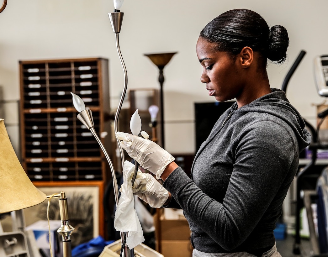 Sergeant Eleanor Peden, embark noncommissioned officer, 15th Marine Expeditionary Unit, cleans a lamp during a volunteer event at The Angel's Depot in Vista, Calif., Sept. 26. All donations go to improving the quality of life for senior citizens. Peden, 25, is from New York.