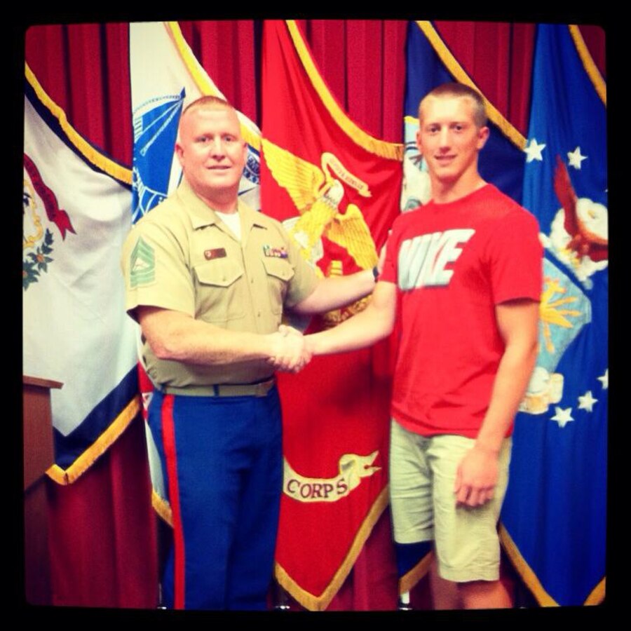 U.S. Marine Corps Master Sgt. Will Caudill, the Operations Chief of Recruiting Station Charleston and native of Charleston, W.Va., congratulates his son Rian after enlisting in the Marine Corps July 9, 2013. Rian, a 17-year-old senior at Cabell Midland and defensive end for the football team, is one of three members of the football team who recently enlisted in the Marine Corps. (Courtesy Photo) 