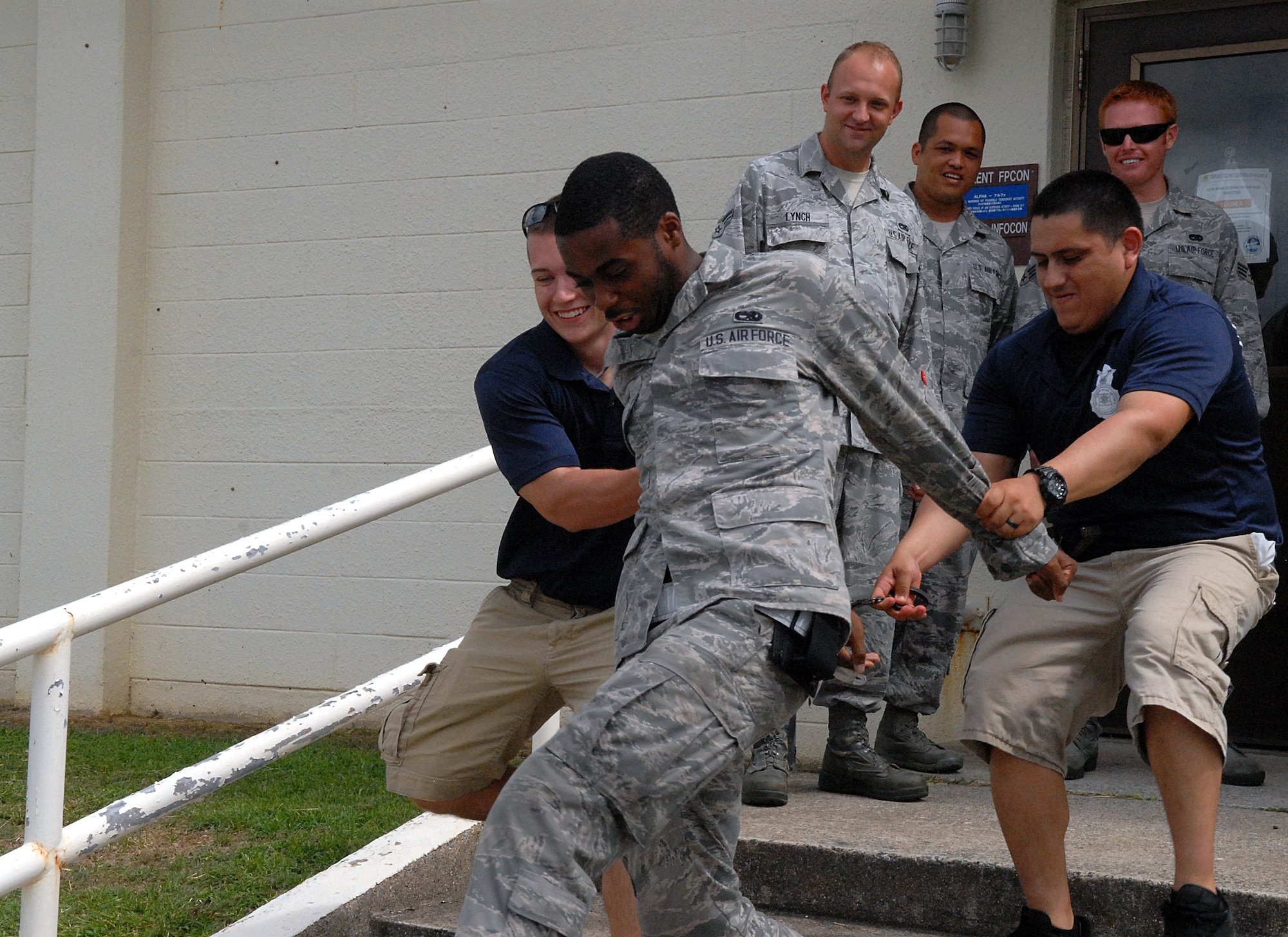 U.S. Air Force Airmen 1st Class Alexander Hainen and Dominic Flores, 18th Security Forces Squadron response force member and leader, arrest Airman 1st Class Jamal Jordan, 18th Aircraft Maintenance Squadron crew chief, as part of a "Jail and Bail" fundraiser Sept. 30, 2013, Kadena Air Base, Japan. Team Kadena members gave rank-based donations to have unsuspecting military members publicly arrested at their place of work and detained in a mock-jail in front of the Exchange. Profits from the fundraiser went toward the Combined Federal Campaign and Shogun Defenders, the squadron's booster club. (U.S. Air Force photo by Staff Sgt. Lauren Snyder)
