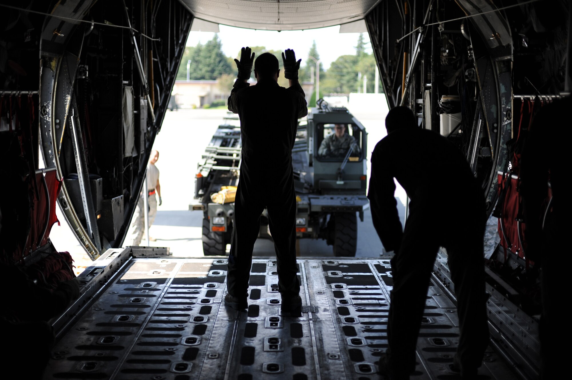 A loadmaster from the 36th Airlift Squadron ushers in a Next Generation Small Loader on a C-130 Hercules at Yokota Air Base, Japan, Sept. 30, 2013. The 36 AS worked with the 374th Logistics Readiness Squadron to support training on loading an NGSL onto the Hercules. (U.S. Air Force photo by Senior Airman Desiree Economides/Released)