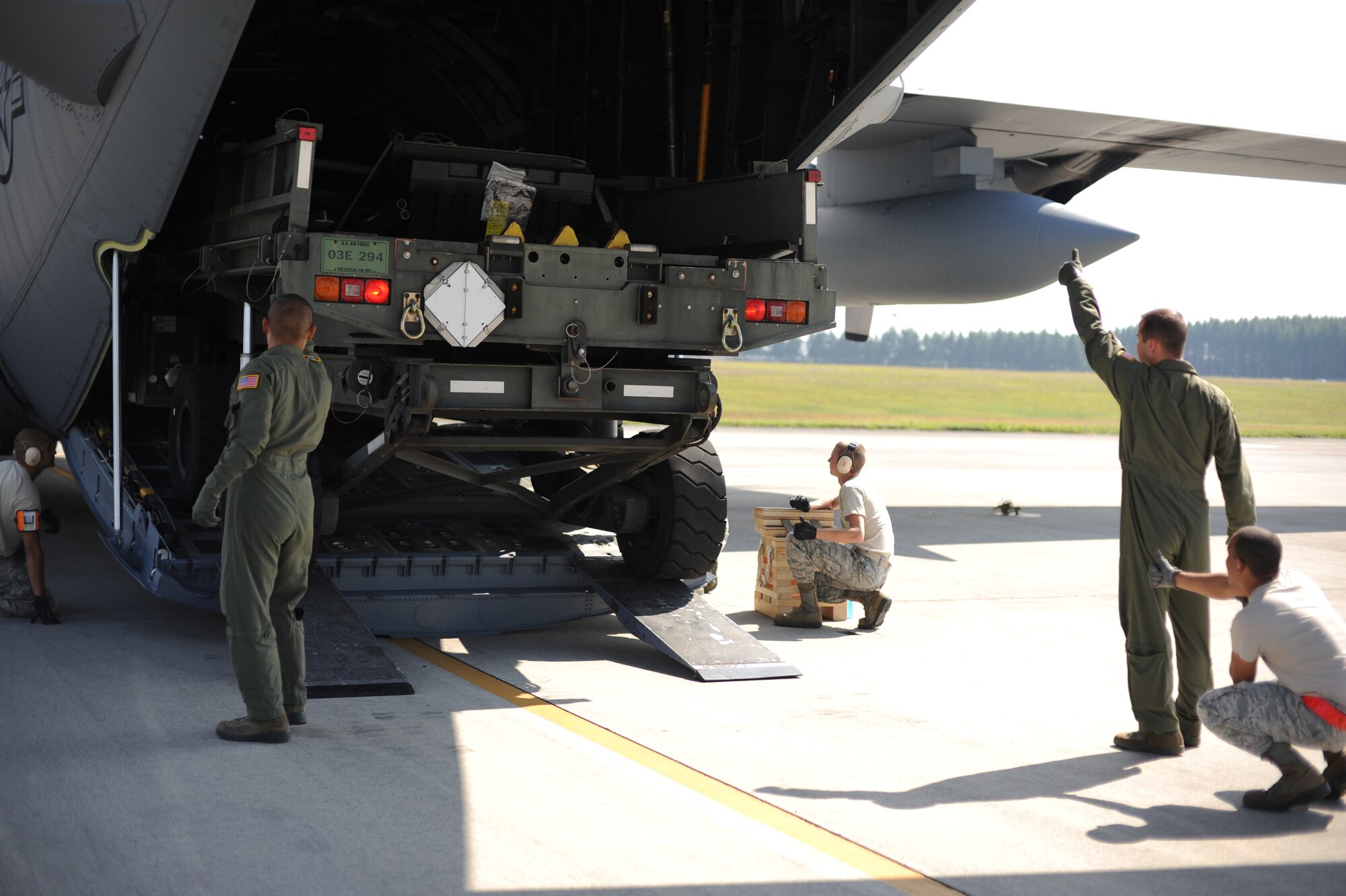 Airmen from the 36th Airlift Squadron and 374th Logistics Readiness Squadron provide safety spot checks as equipment is loaded onto a C-130 Hercules Sept. 30, 2013, at Yokota Air Base, Japan. The 36 AS and 374 LRS worked together to conduct training on loading heavy equipment onto a C-130. (U.S. Air Force photo by Senior Airman Desiree Economides/Released)
