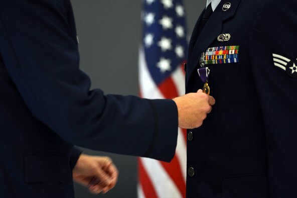 Col. Craig Gaddis, 62nd Maintenance Group commander, pins the Purple Heart medal to the service coat of Senior Airmen Anthony Haupert, 62nd Aircraft Maintenance Squadron communications and navigation systems specialist, Sept. 27, 2013, at Joint Base Lewis-McChord, Wash. Haupert received the medal for injuries received during a deployment to Afghanistan in 2012. (U.S. Air Force photo/Staff Sgt. Jason Truskowski)