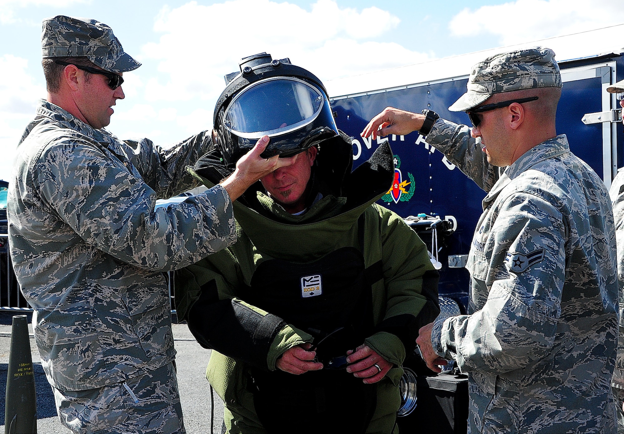 Capt. John Pickering, 436th Civil Engineer Squadron explosive ordinance disposal flight commander, and Airman 1st Class Andrew Vitale, 436th CES EOD apprentice, help Frank Rusek put on bomb squad suit Sept. 29, 2013, at Dover International Speedway in Dover, Del. The bomb squad volunteered during race weekend to demonstrate their capabilities to the public. (U.S. Air Force photo/Airman 1st Class Ashlin Federick)
