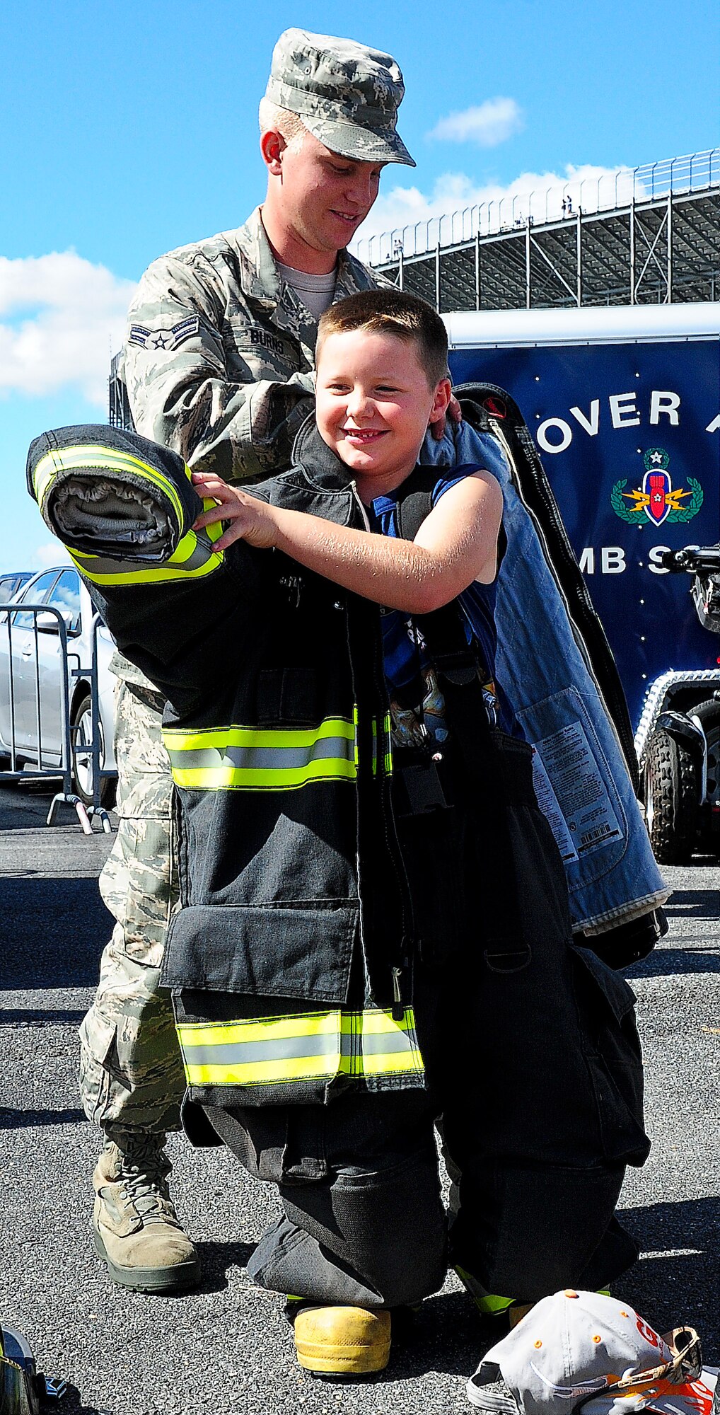 Airman 1st Class Christopher Burns, 436th Civil Engineer Squadron firefighter, helps Rielley Ketterman put on a firefighter suit Sept. 29, 2013, at Dover International Speedway in Dover, Del. The Dover Air Force Base fire department was in the Monster Fun Zone to teach the public about fire prevention. (U.S. Air Force photo/Airman 1st Class Ashlin Federick)