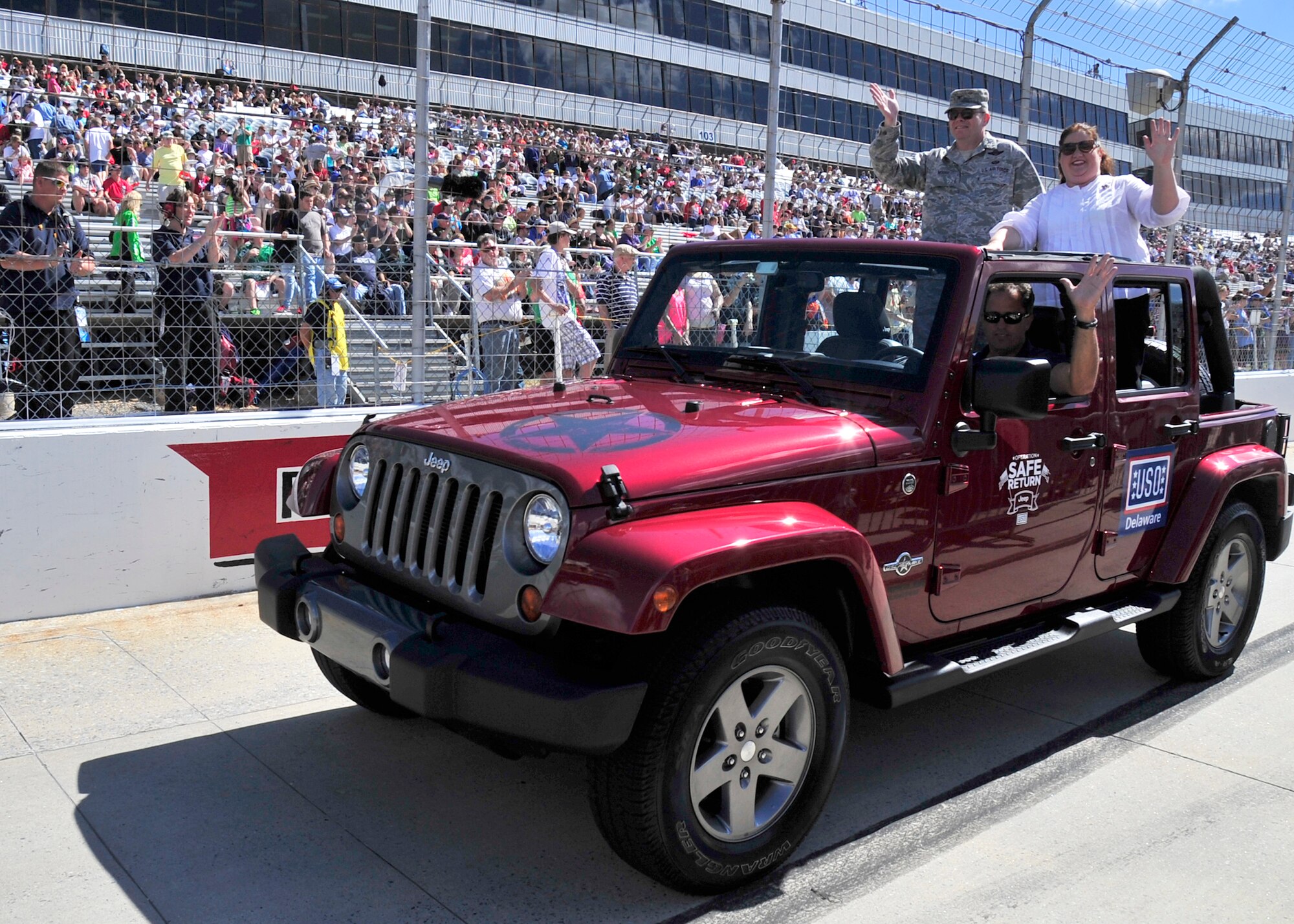 Col. Rick Moore, 436th Airlift Wing commander, and his wife Kristin, wave to the crowd before the start of the AAA 400 Sept. 29, 2013, at Dover International Speedway in Dover, Del. Col. Moore was part of the big Team Dover presence at the track during race weekend. (U.S. Air Force photo/Tech. Sgt. Chuck Walker)